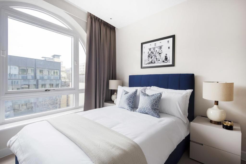 a bedroom with a large bed with a large window at Buckingham Palace Residences by Aeria Apartments in London