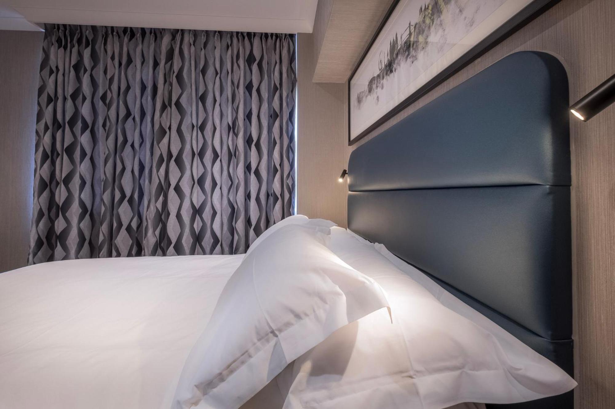 a bedroom with a white bed with a black headboard at City Sleeper at Royal National Hotel in London