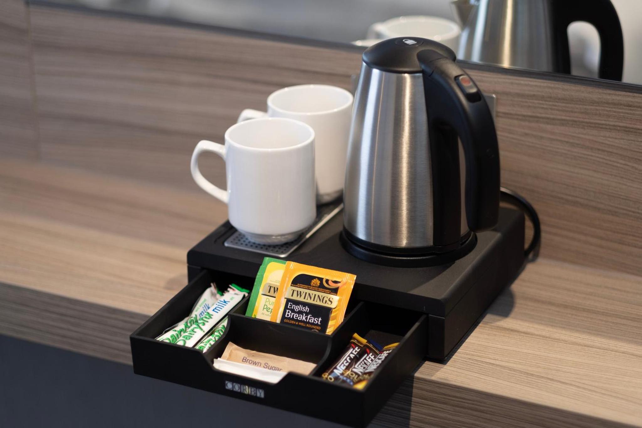 a coffee maker and cups on a counter at City Sleeper at Royal National Hotel in London