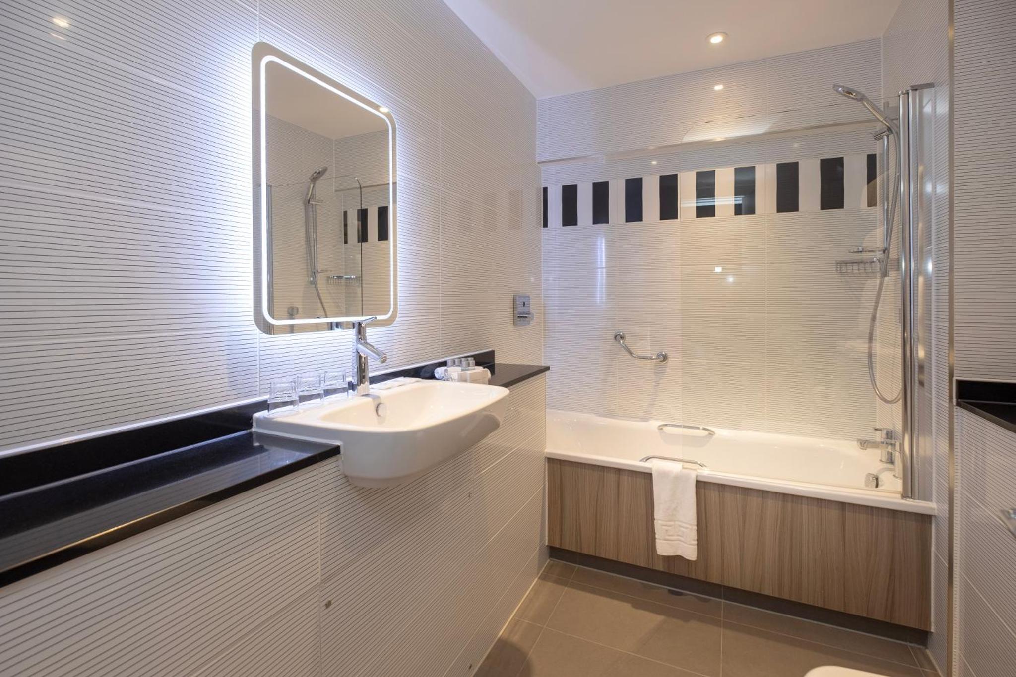 a bathroom with a sink and a tub and a mirror at City Sleeper at Royal National Hotel in London +17 photos