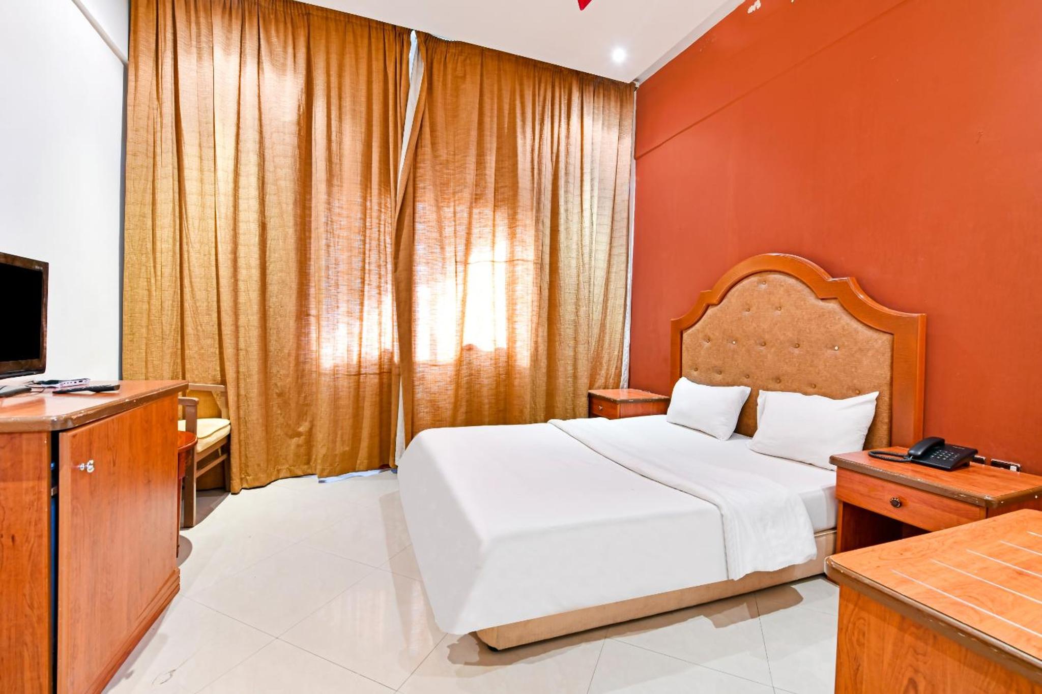 a hotel room with a bed and a television at OYO 118 Revira Hotel in Manama