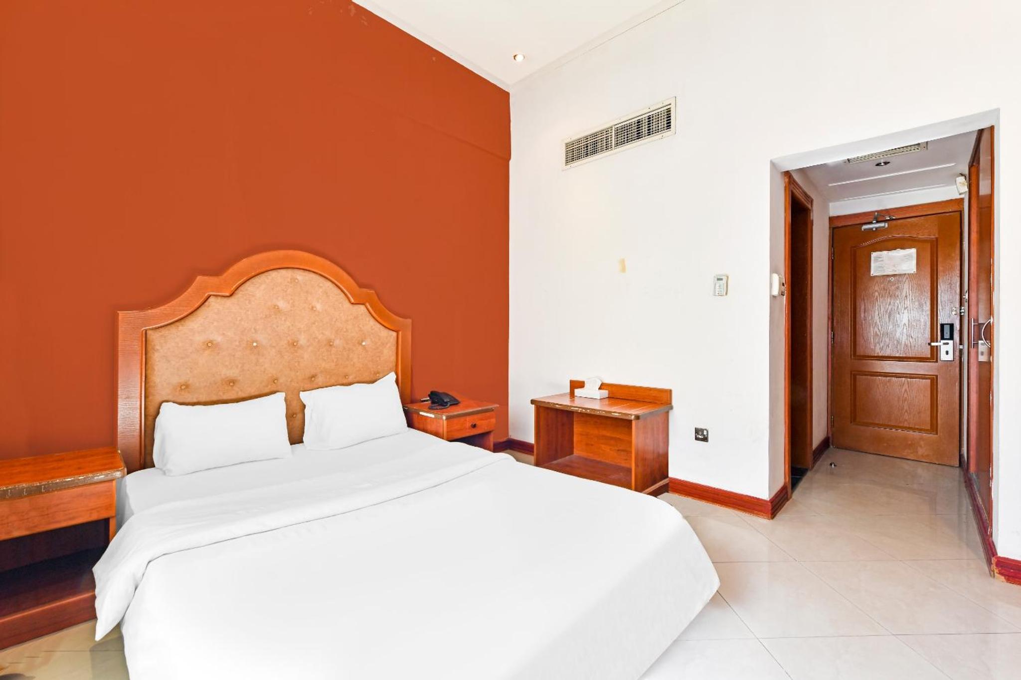 a bedroom with a white bed and an orange wall at OYO 118 Revira Hotel in Manama +37 photos