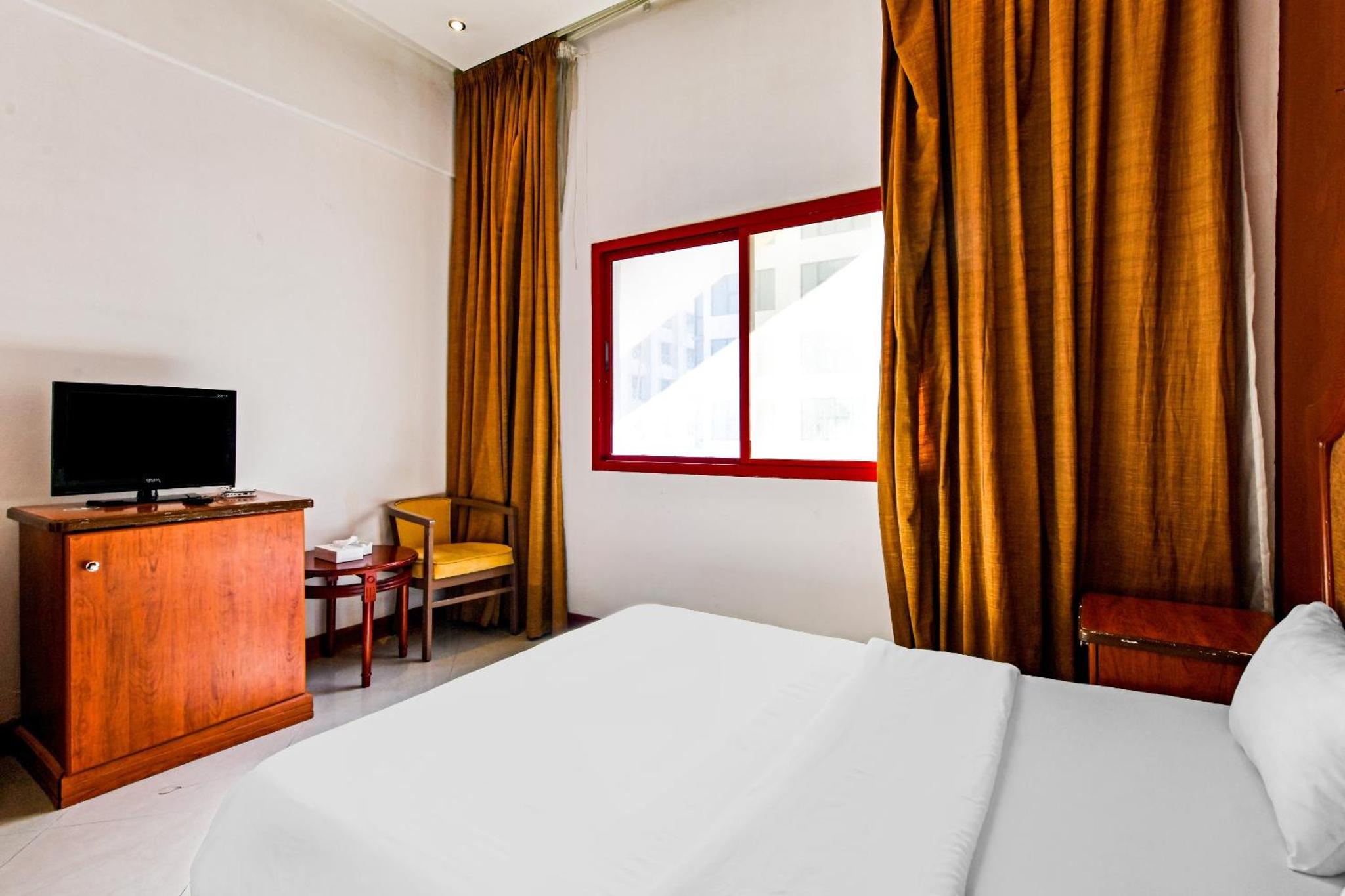 a bedroom with a bed and a television and a window at OYO 118 Revira Hotel in Manama