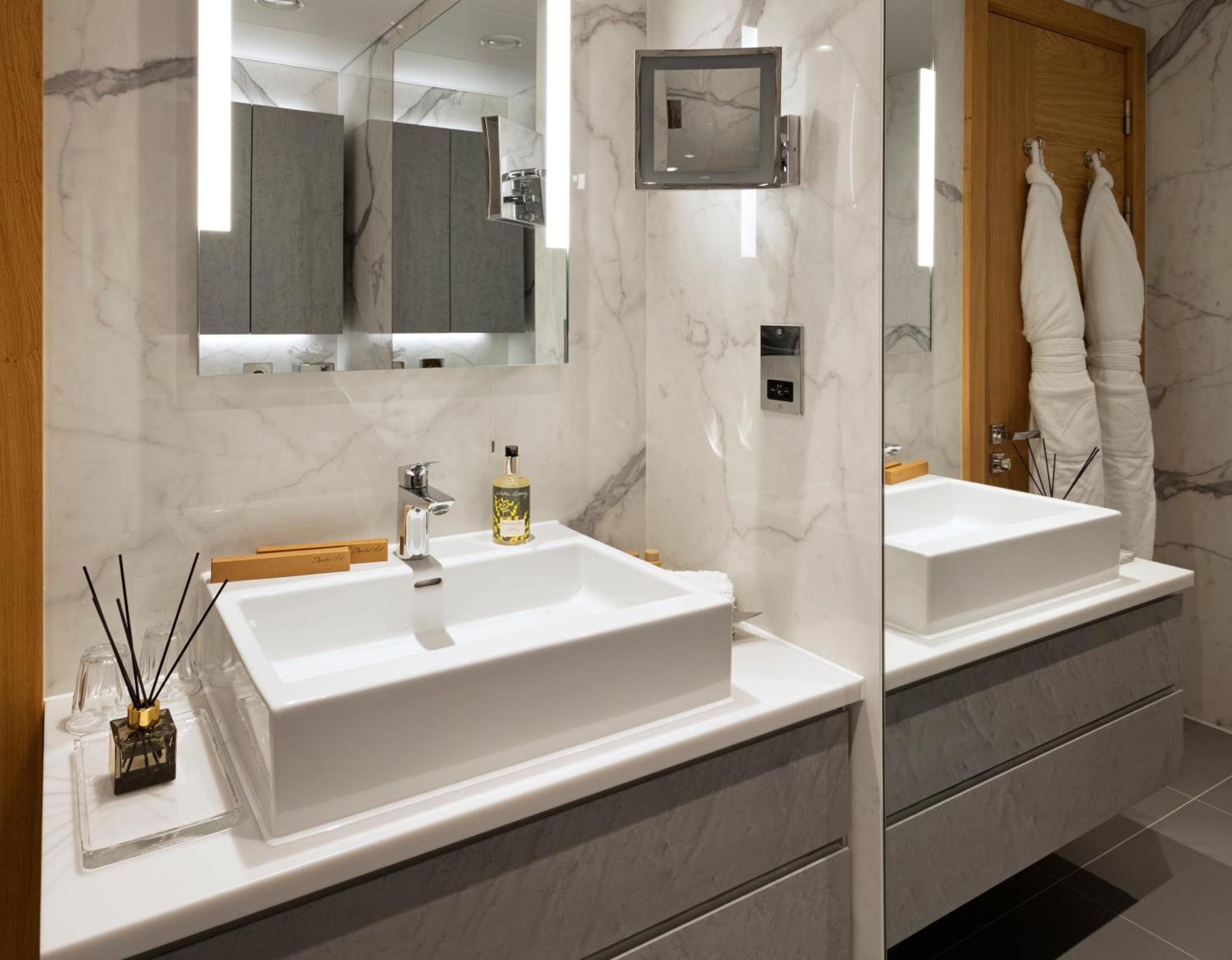 a white bathroom with two sinks and a mirror at Tower Suites by Blue Orchid in London +30 photos