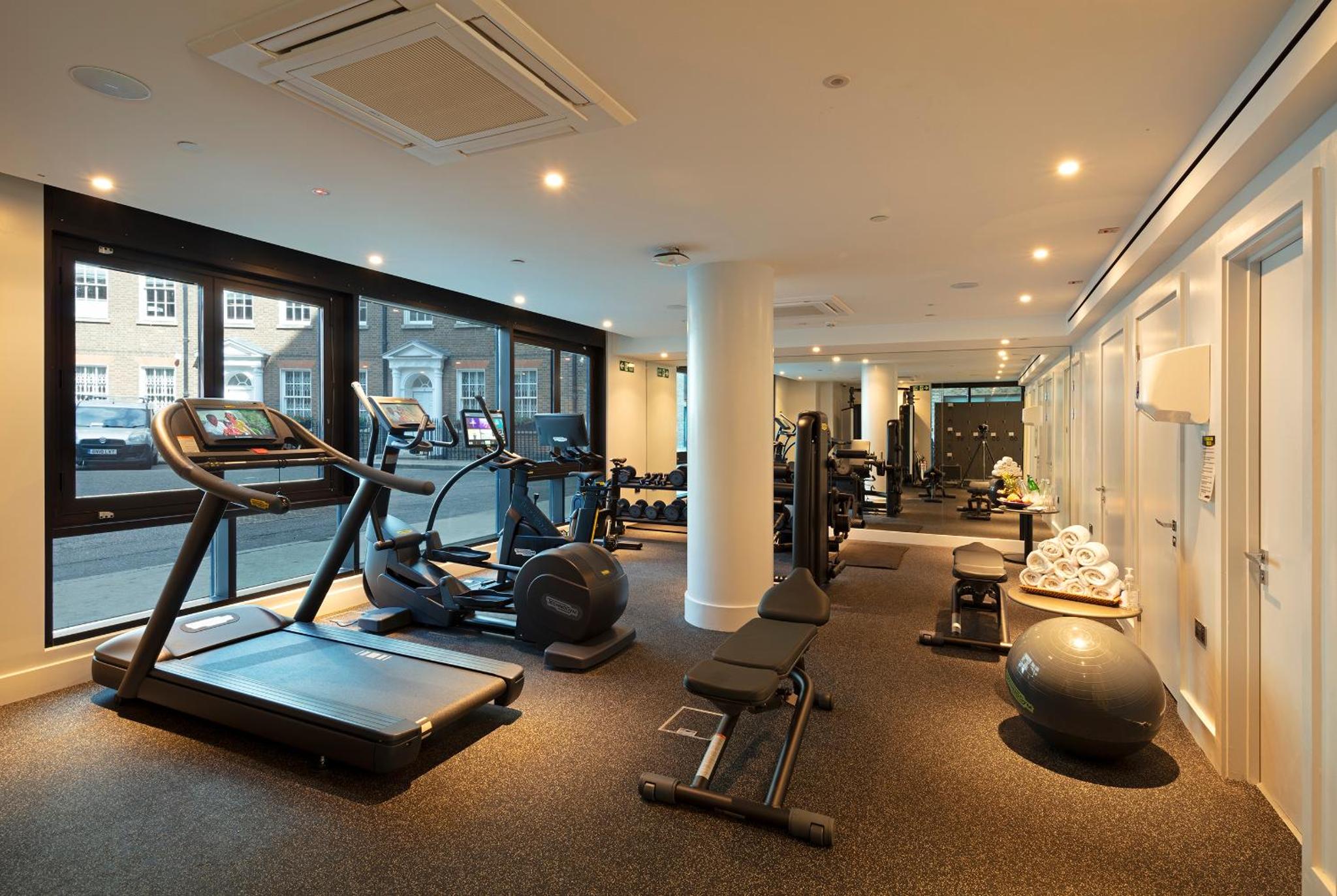 a gym with treadmills and cardio equipment in a building at Tower Suites by Blue Orchid in London