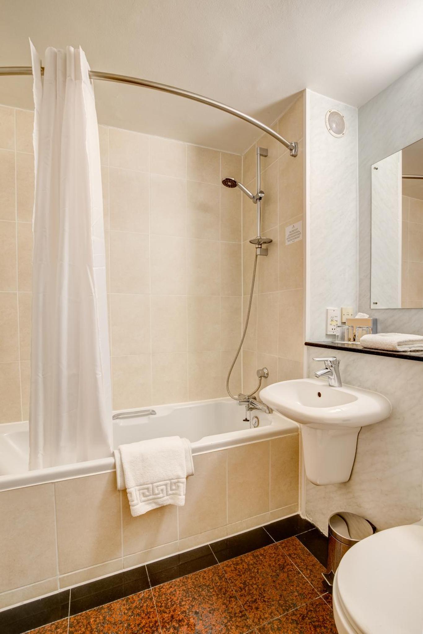 a bathroom with a tub and a sink and a toilet at Copthorne Tara Hotel London Kensington in London