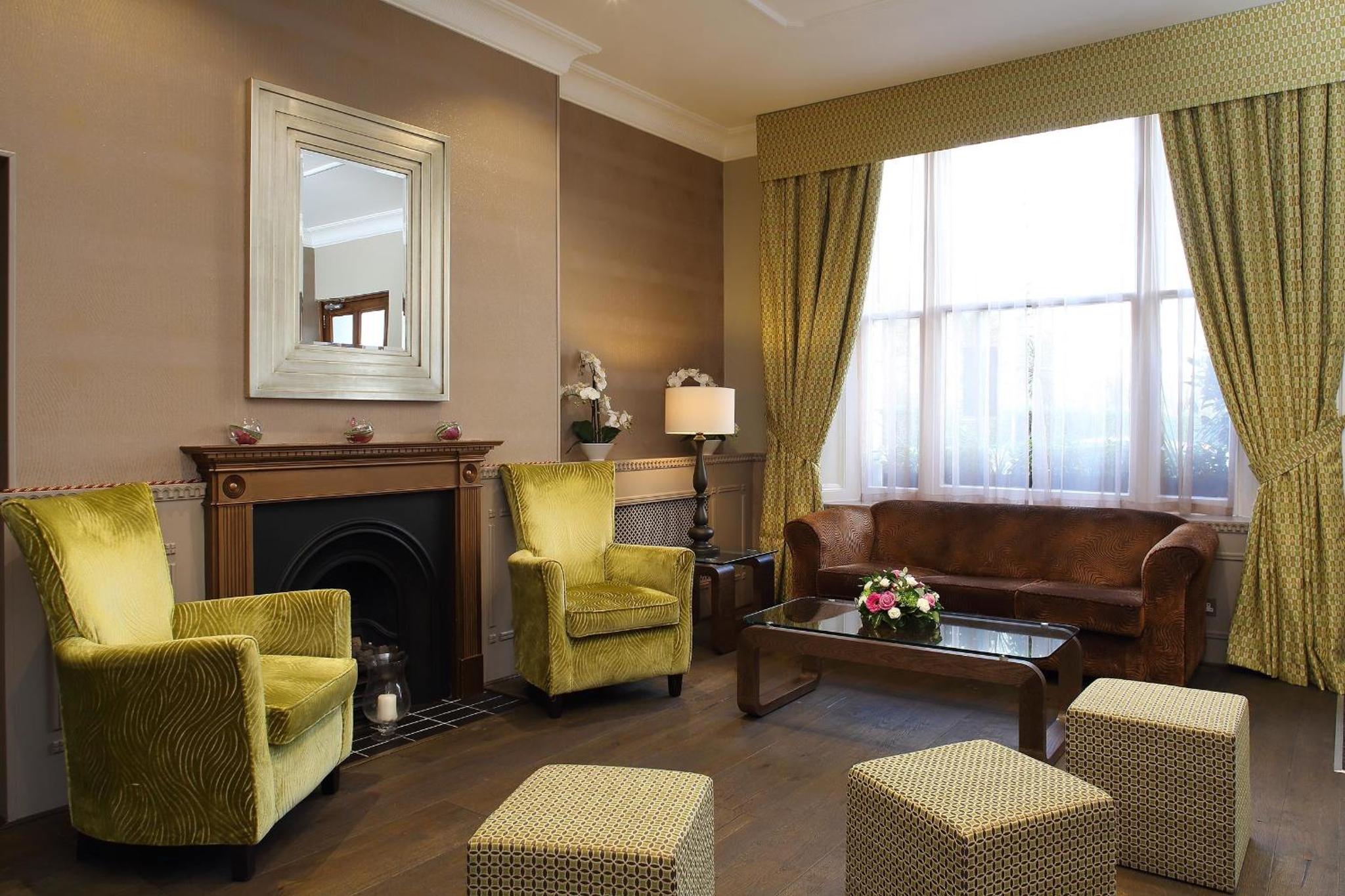 a living room with a fireplace and chairs and a mirror at Phoenix Hotel in London