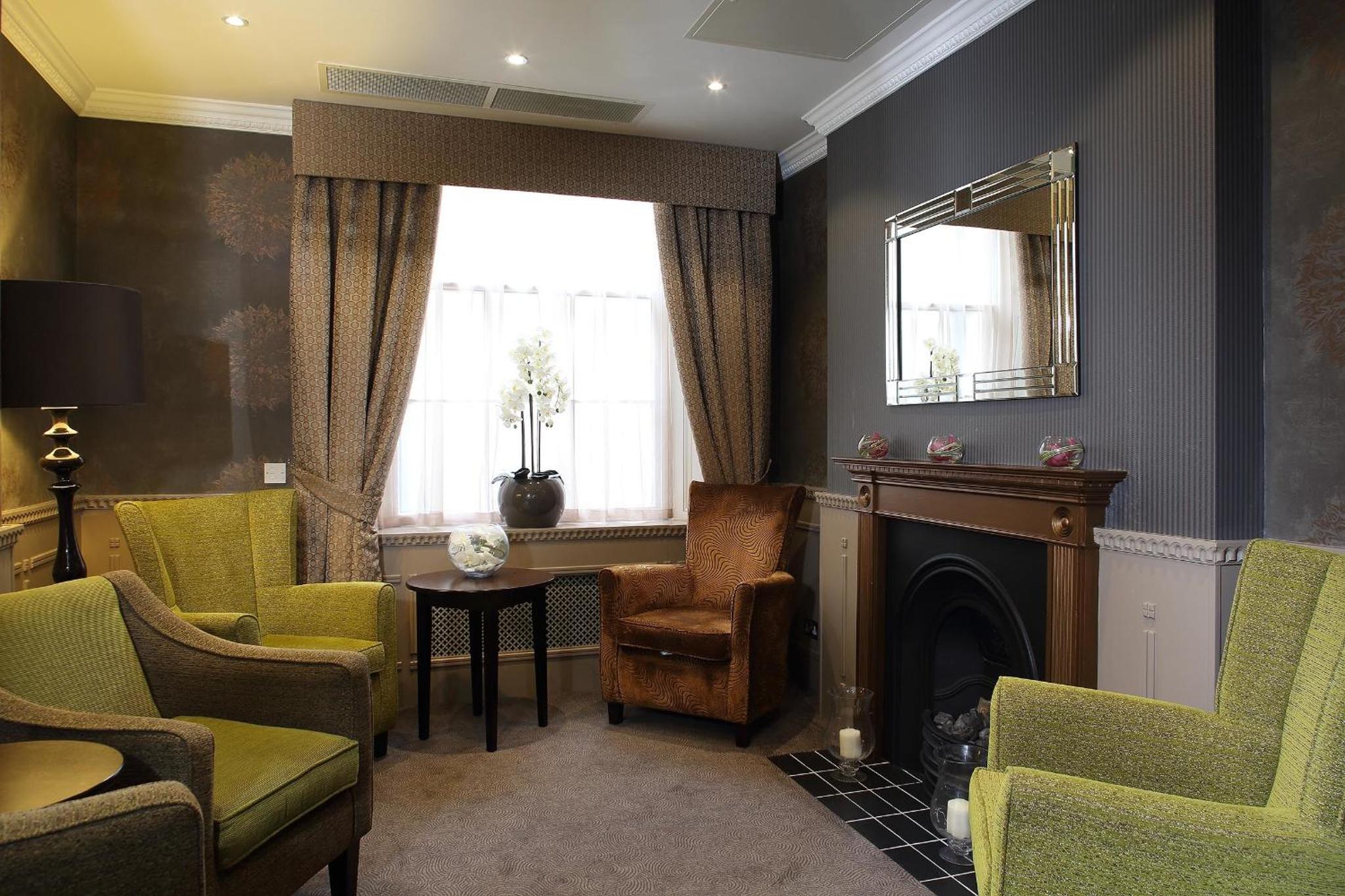 a living room with chairs and a fireplace and a mirror at Phoenix Hotel in London