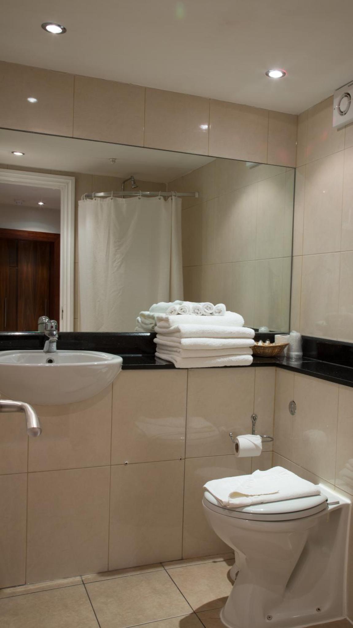 a bathroom with a sink and a toilet and a mirror at Garden View Hotel in London +31 photos