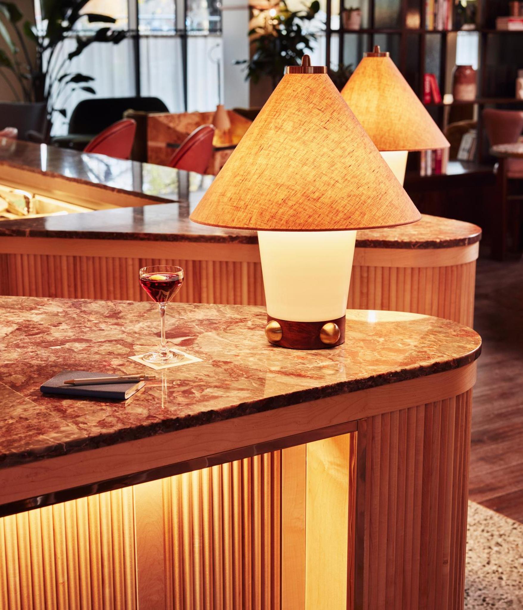 a table with a lamp and a glass of wine at The Hoxton, Shepherds Bush in London