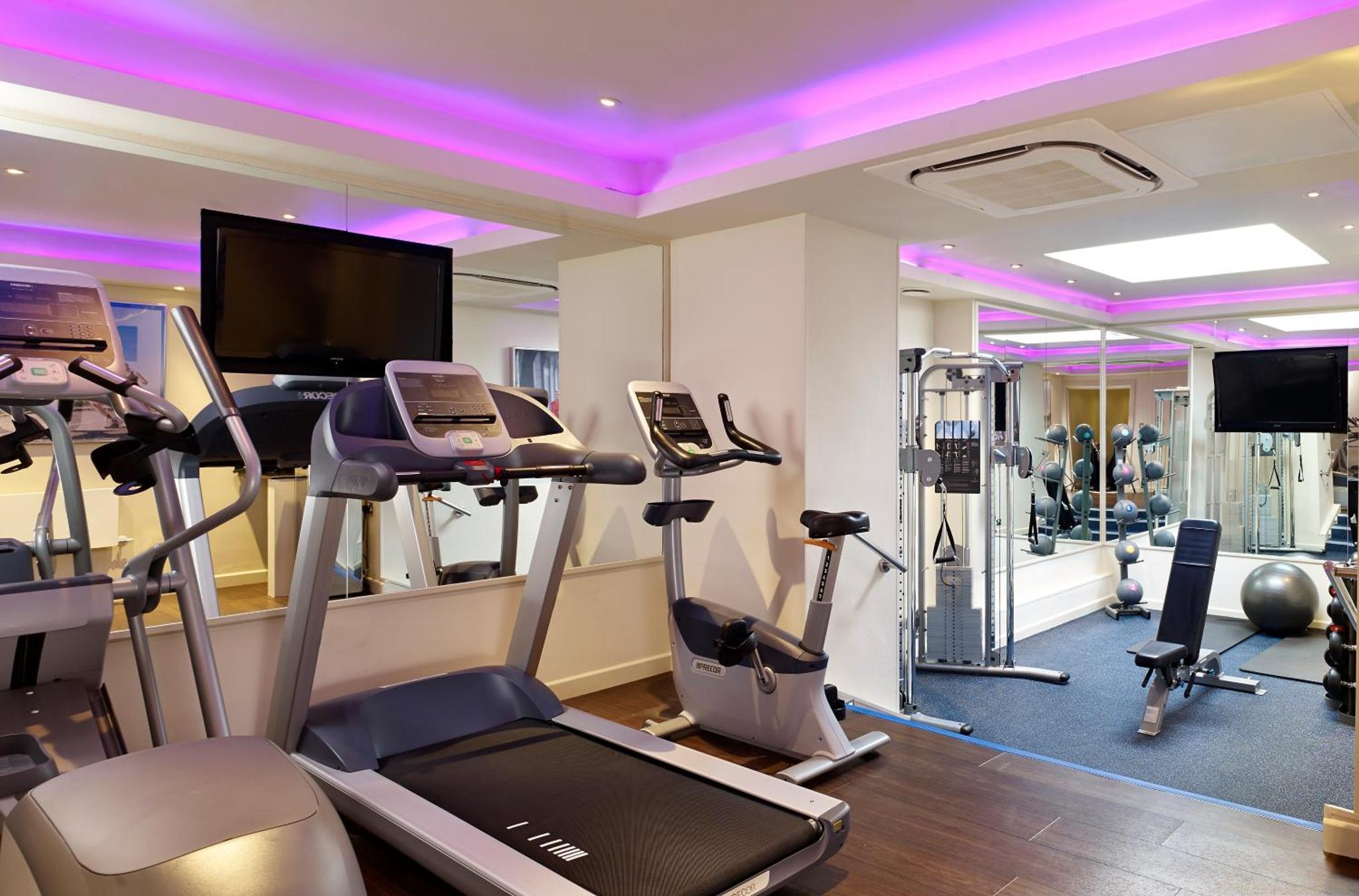 a gym with treadmills and cardio equipment in a room at Blakemore Hyde Park in London