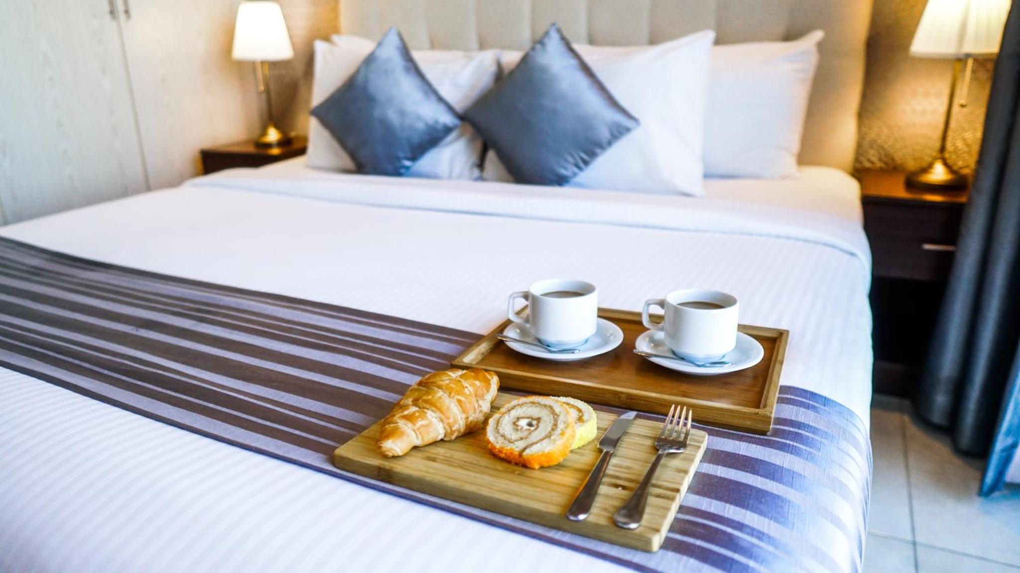 a tray of croissants and coffee cups on a bed at Loumage S Suites and Spa in Manama +55 photos