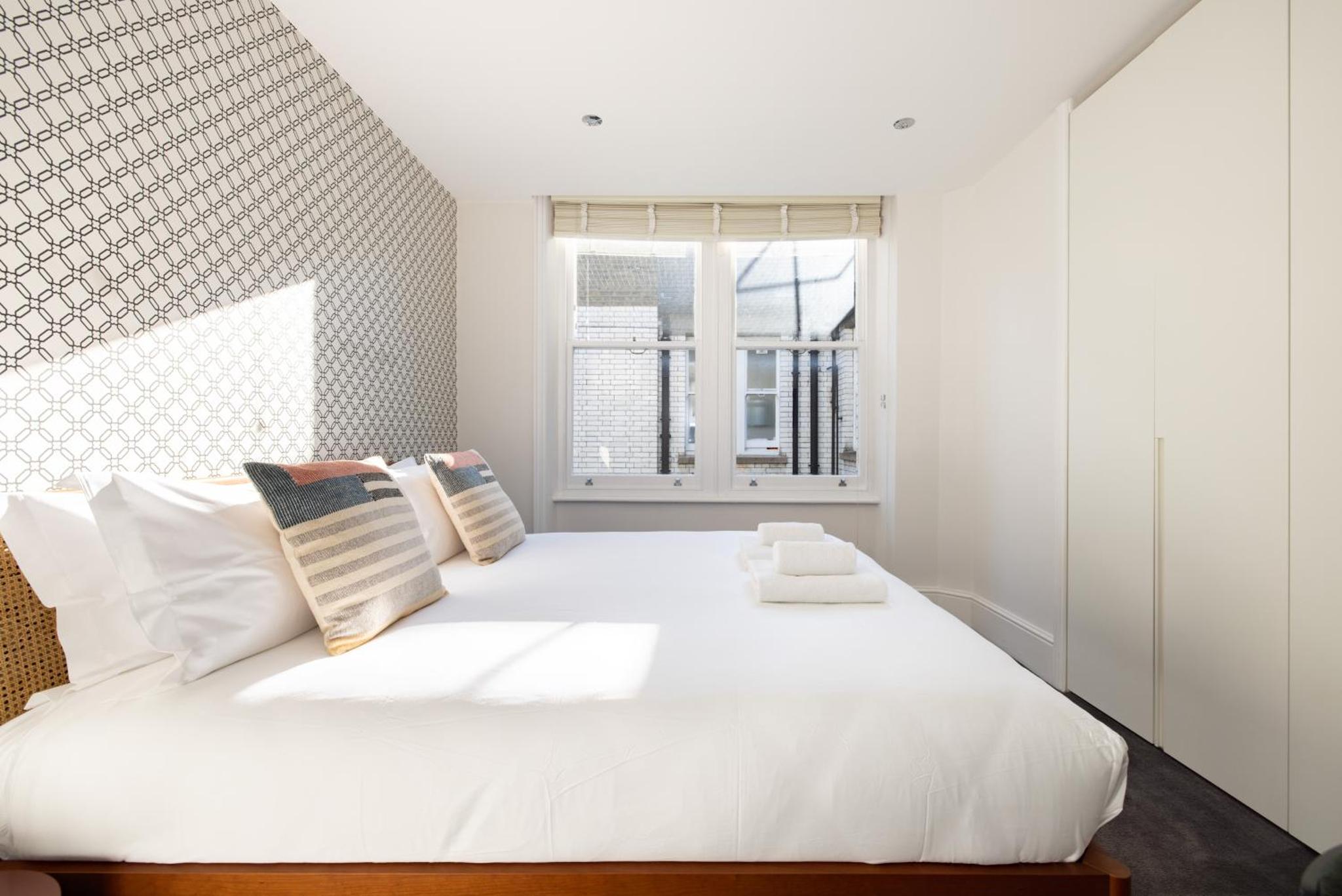 a white bedroom with a large bed and a window at Hausd Flex - Covent Garden in London
