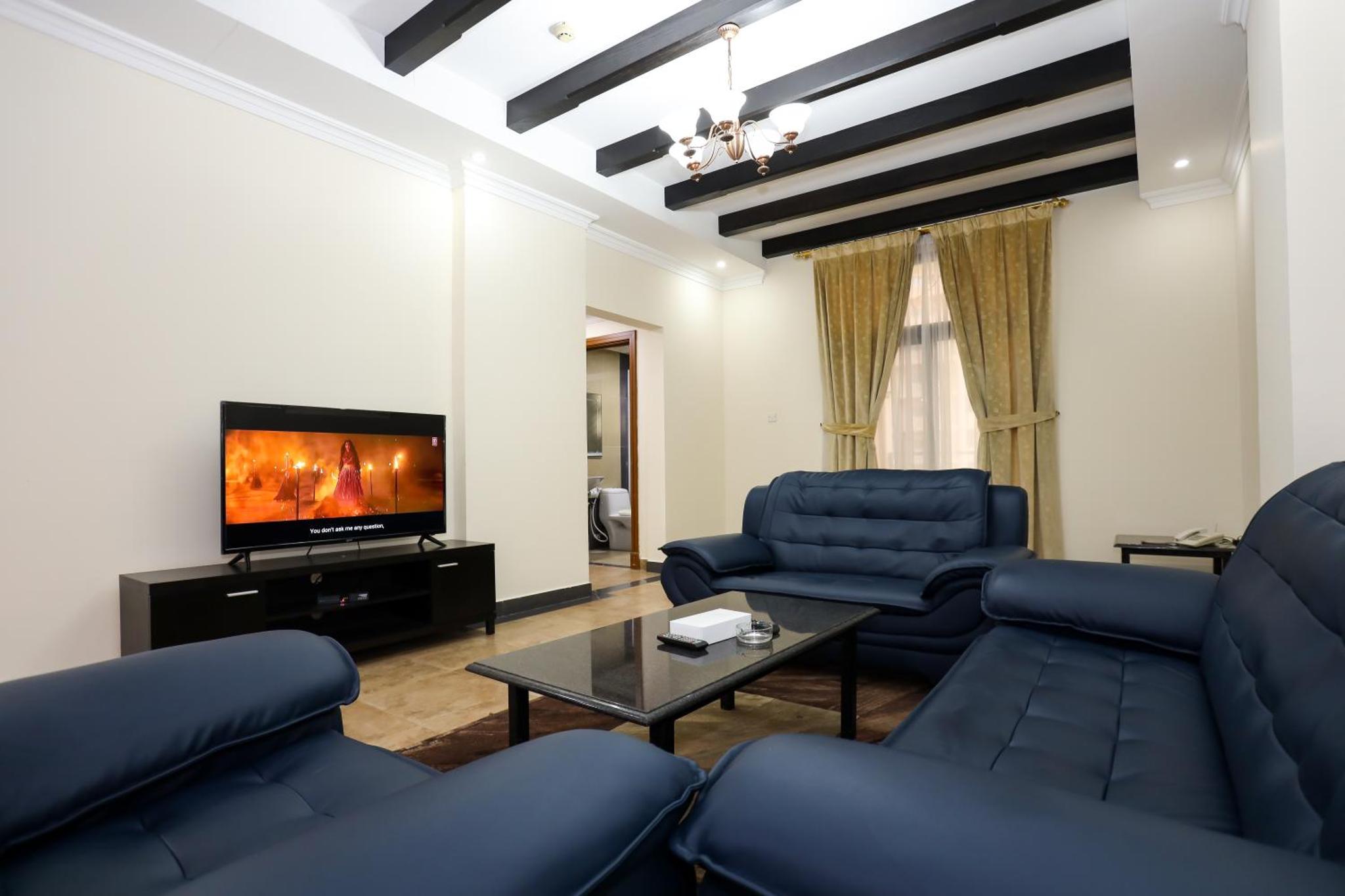 a living room with blue couches and a tv at Pearl Bahrain Suites in Manama