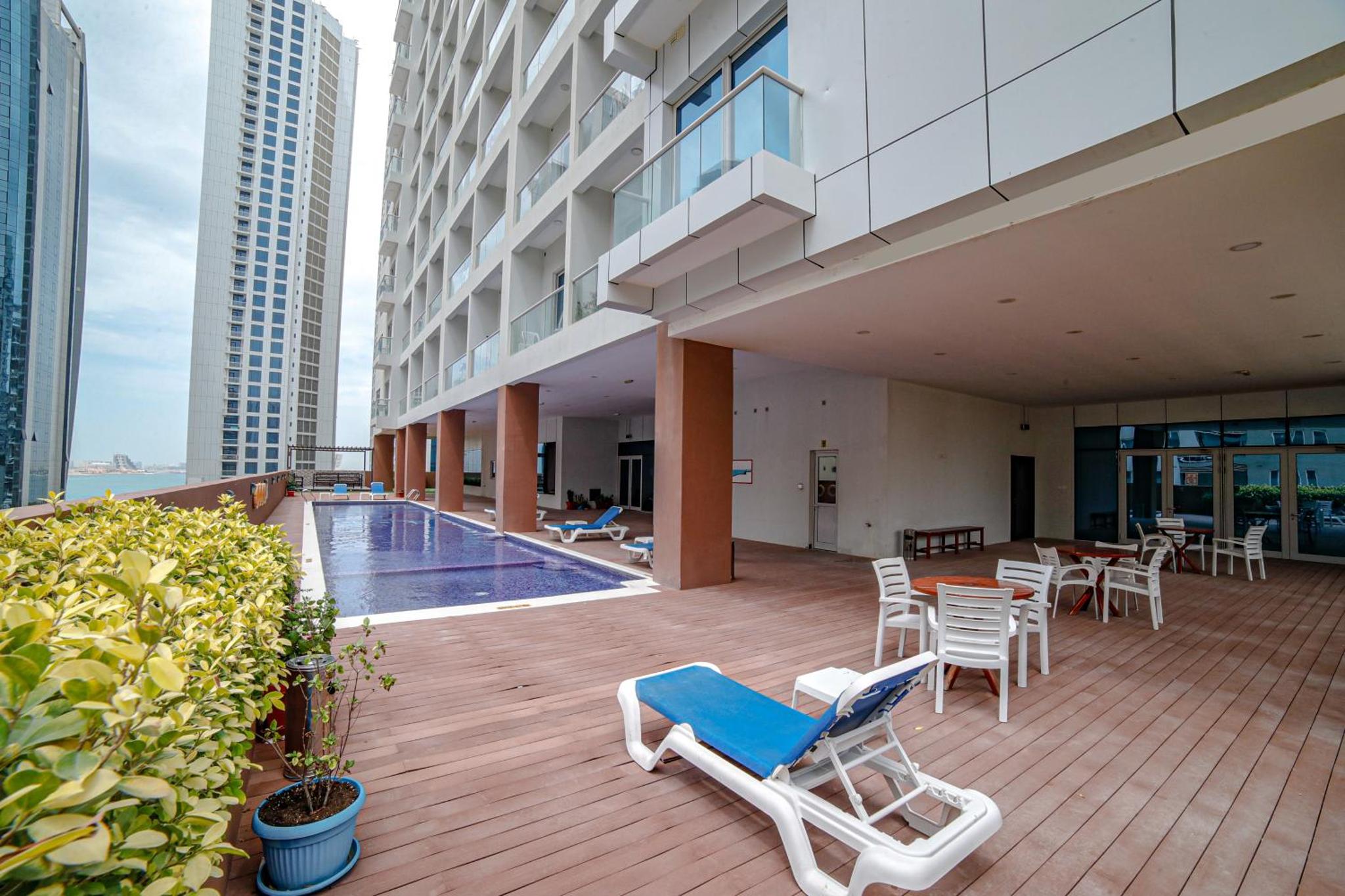 a deck with lounge chairs and a pool on a building at Vita Suites in Manama