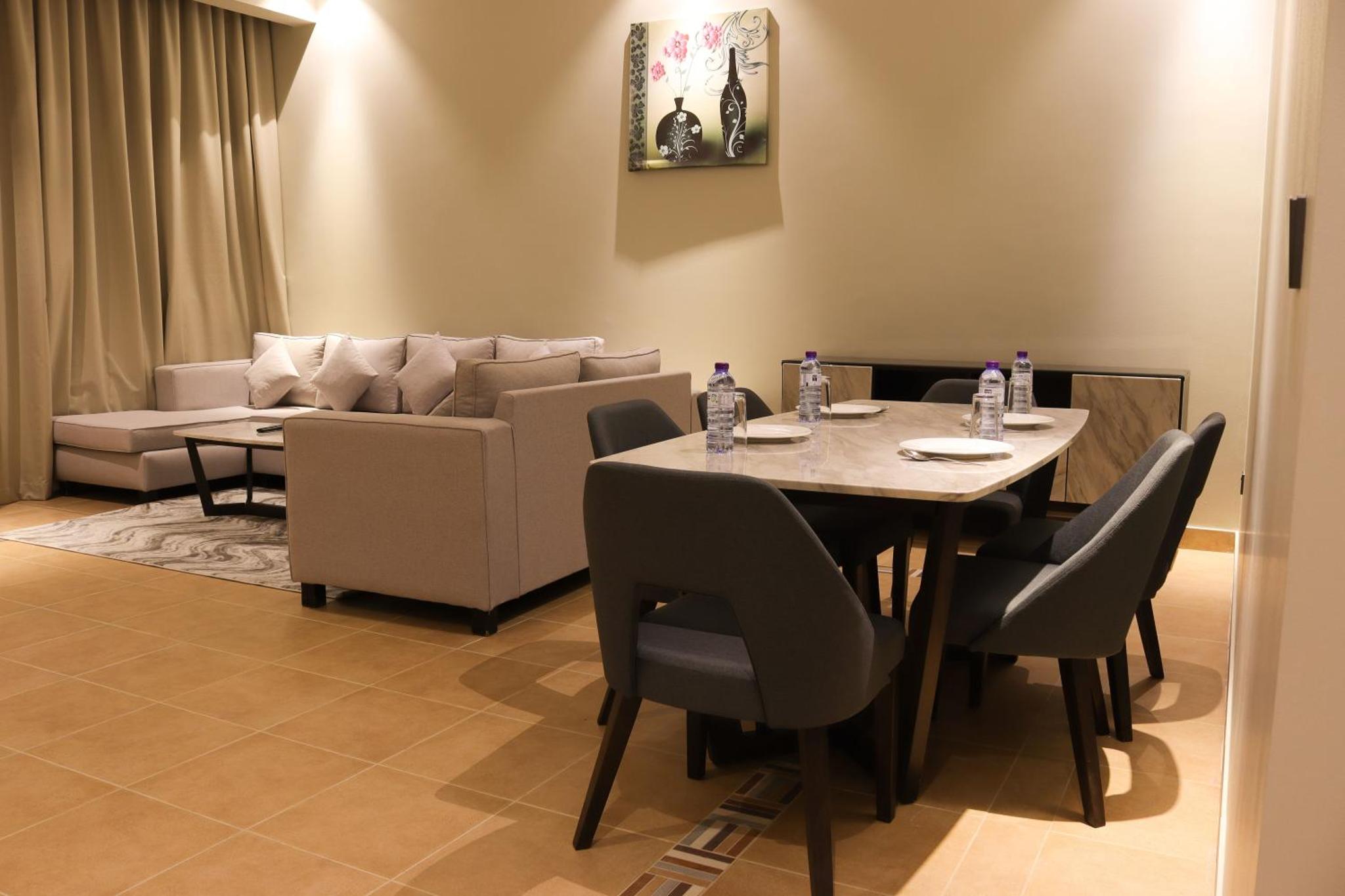 a dining room with a table and a couch at Infinity Tower Suites WLL in Manama