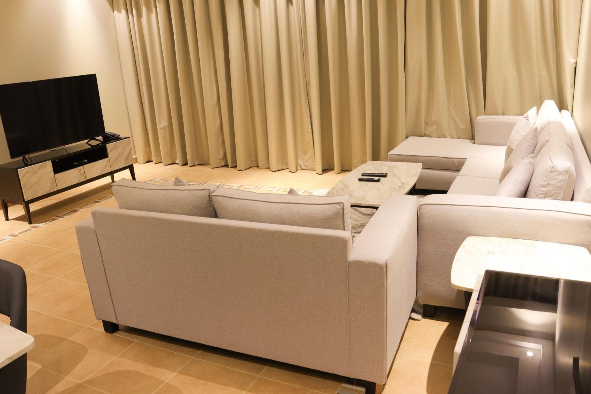 a living room with white couches and a flat screen tv at Infinity Tower Suites WLL in Manama