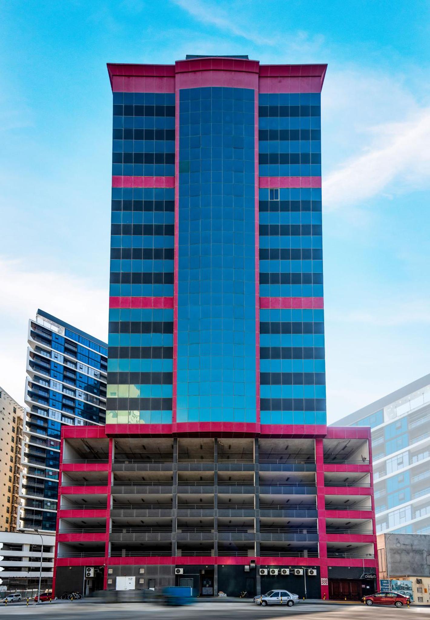 a tall blue and red building in a city at Diva Hotel in Manama
