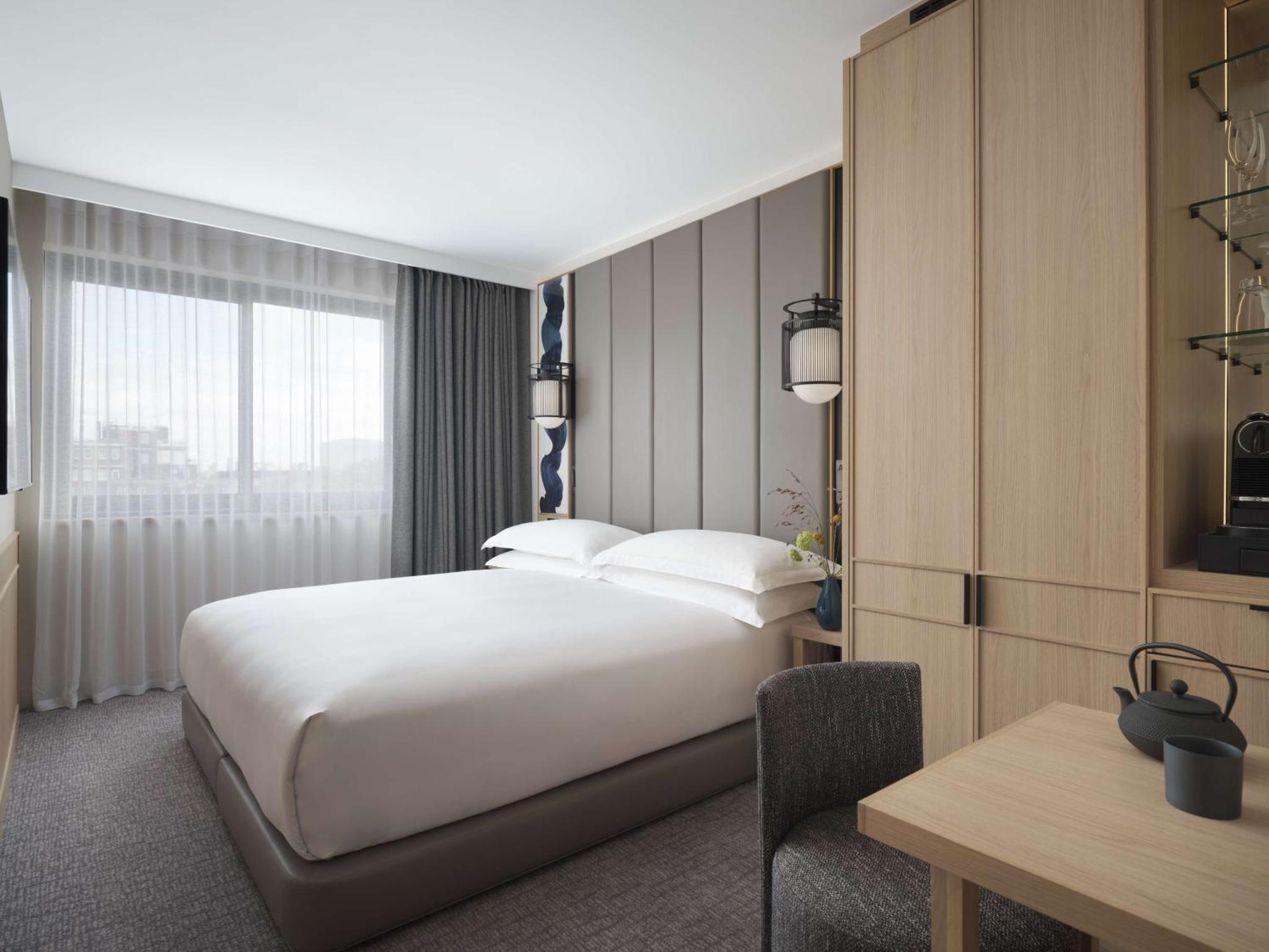a hotel room with a large bed and a desk at Nobu Hotel London Portman Square in London