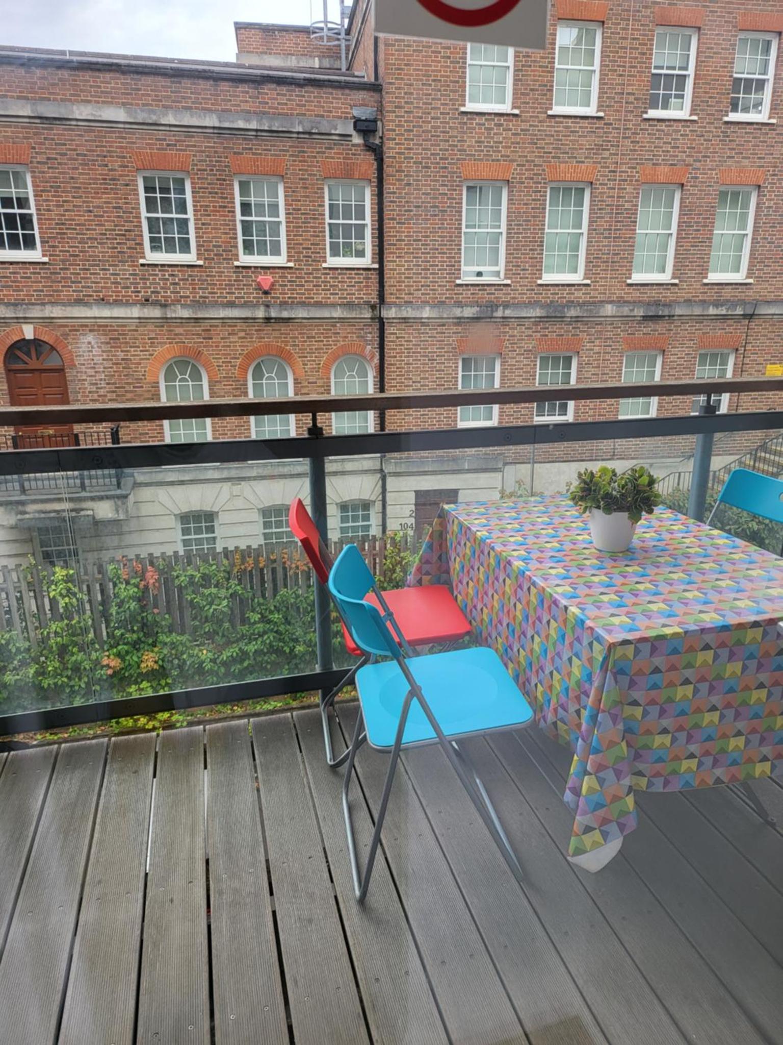 a table and chairs sitting on a deck with a table and a building at WALKING TO TOWER BRIDGE in London