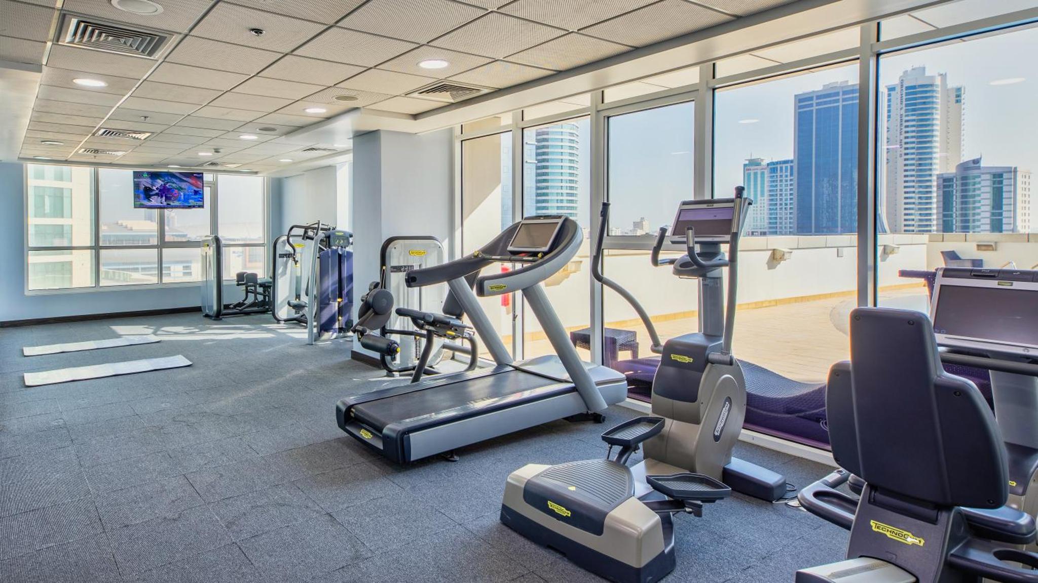 a gym with cardio equipment and a view of the city at S Hotel Bahrain in Manama