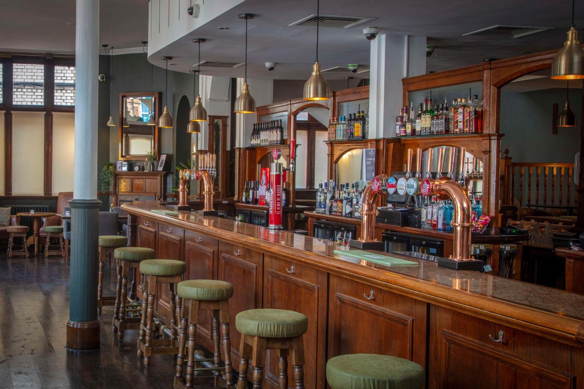 a bar with a bunch of stools in a room at The Crown London Hotel, Cricklewood North West London, WorldHotels Distinctive in London
