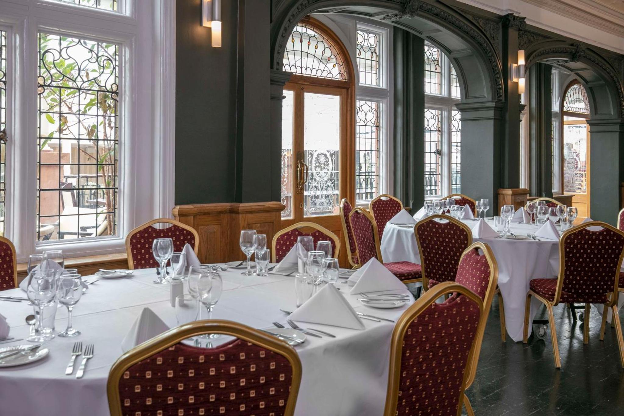 a dining room with white tables and chairs and windows at The Crown London Hotel, Cricklewood North West London, WorldHotels Distinctive in London