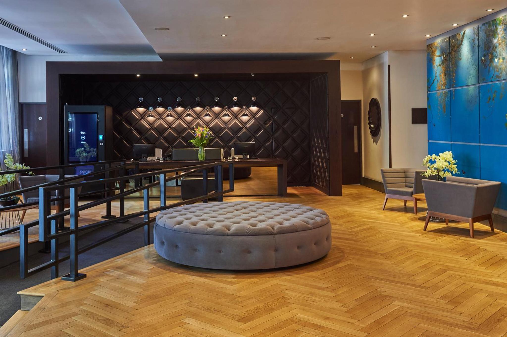 a lobby with a round ottoman in the middle of a room at Malmaison London in London