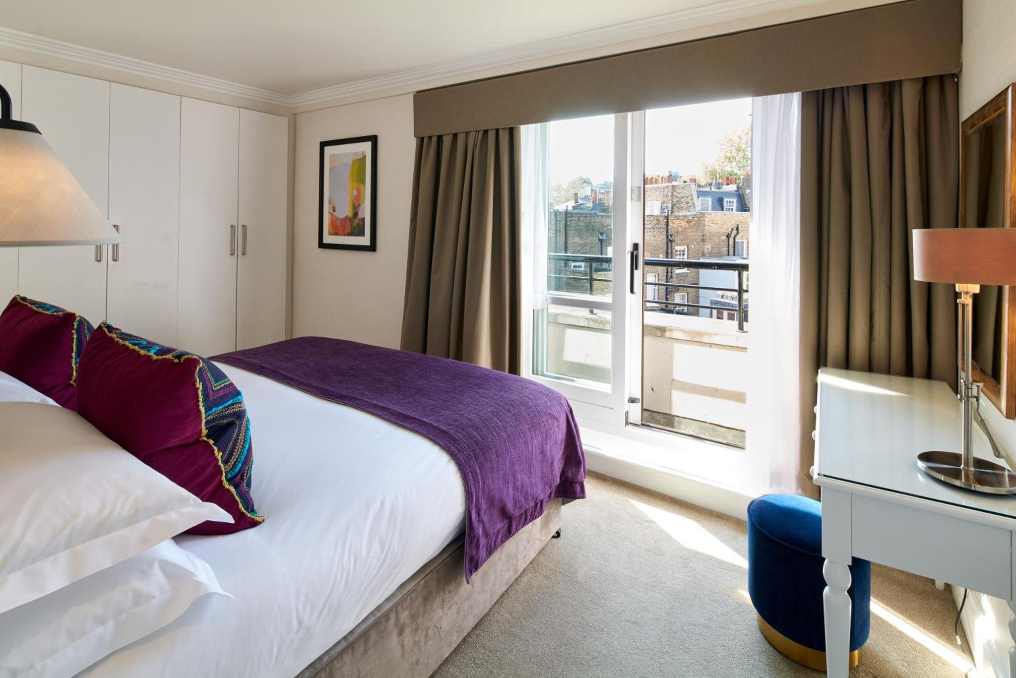 a hotel room with a bed and a window at Cheval Knightsbridge in London