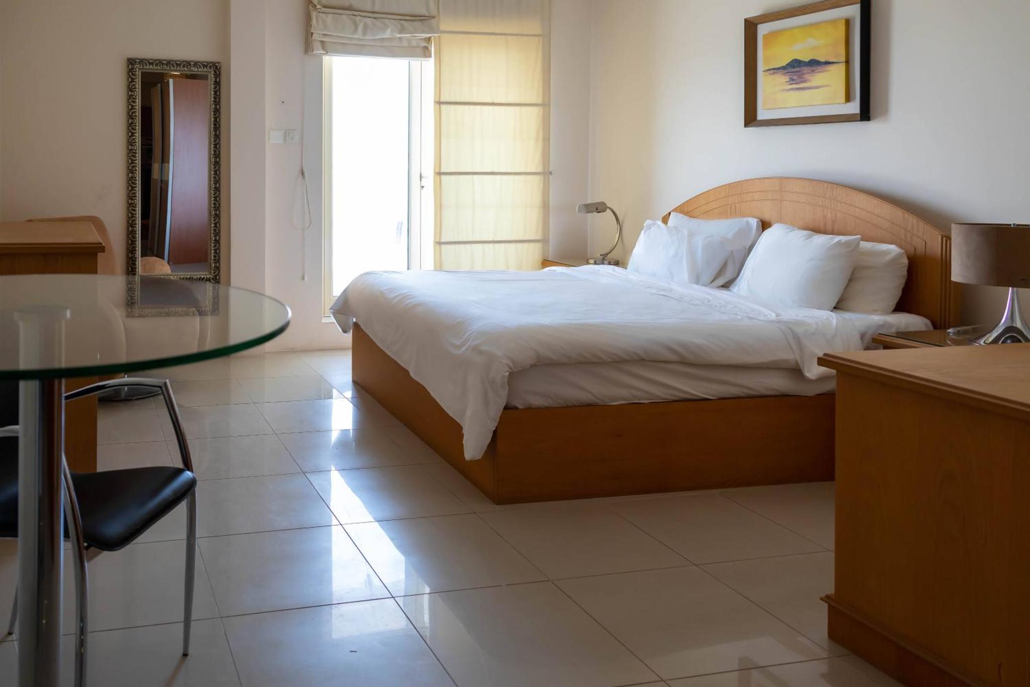 a bedroom with a bed and a glass table at Mansouri Mansions Hotel in Manama