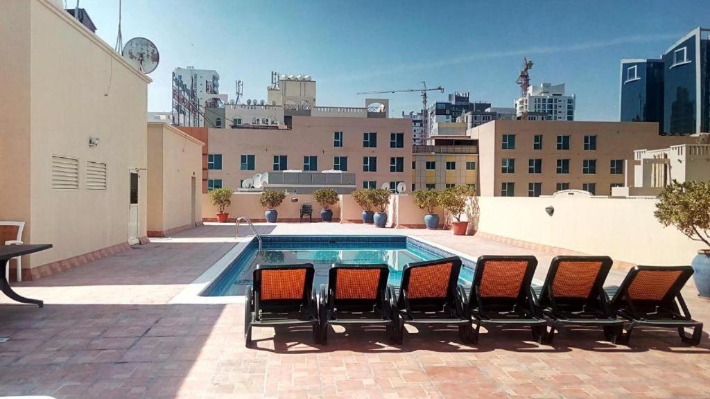 a group of chairs sitting next to a swimming pool at Alzebara 2 Apartment in Manama