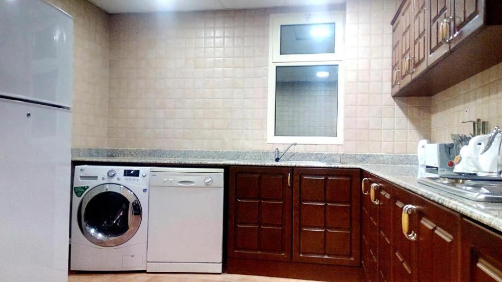 a kitchen with a washing machine and a window at Alzebara 2 Apartment in Manama