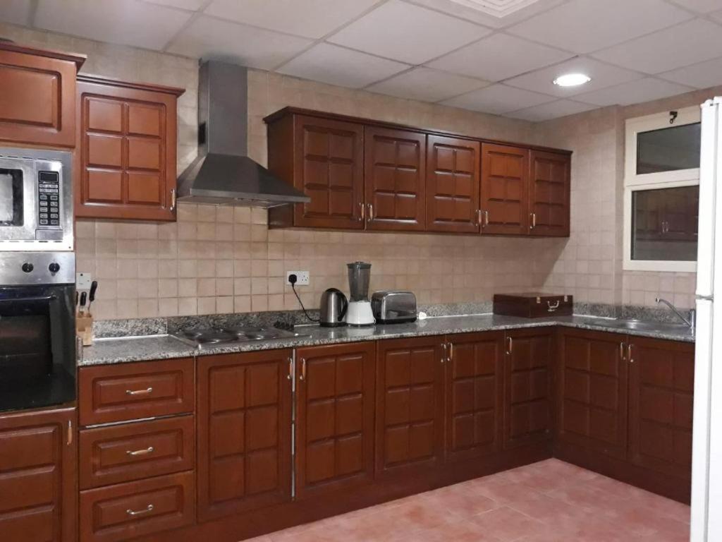 a kitchen with wooden cabinets and a microwave at Alzebara 2 Apartment in Manama