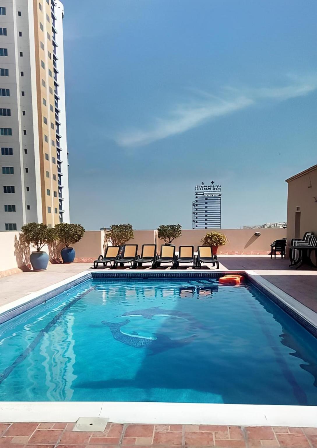 a swimming pool with chairs in a building at Alzebara 2 Apartment in Manama