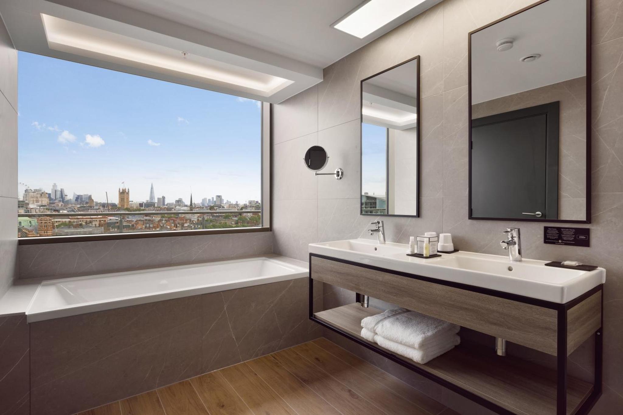 a bathroom with a tub and a sink and a window at Riu Plaza London Victoria in London