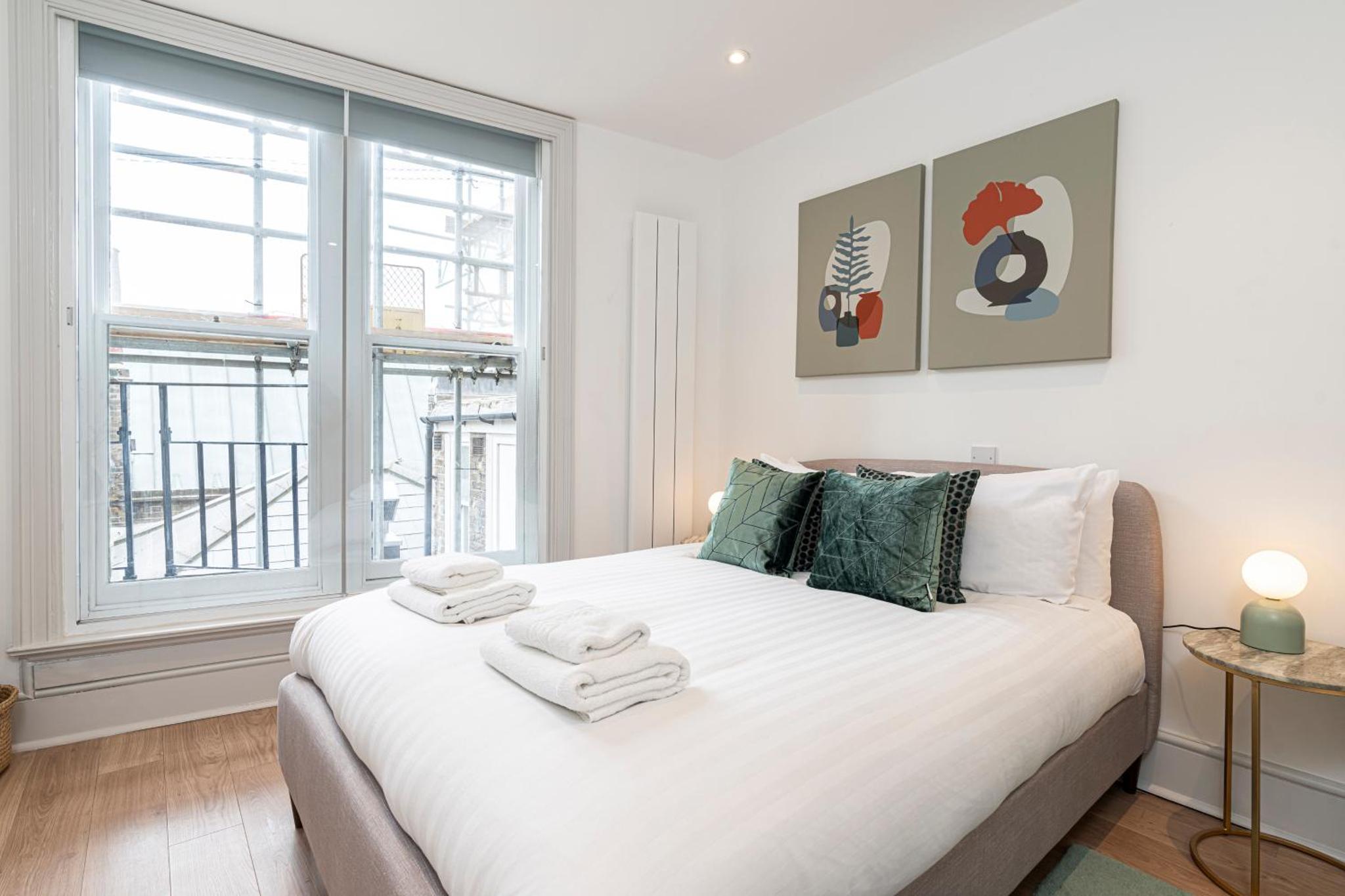 a bedroom with a large white bed with towels on it at Stylish 1 bed flats in Soho, next to Piccadilly Circus and Trafalgar Square in London