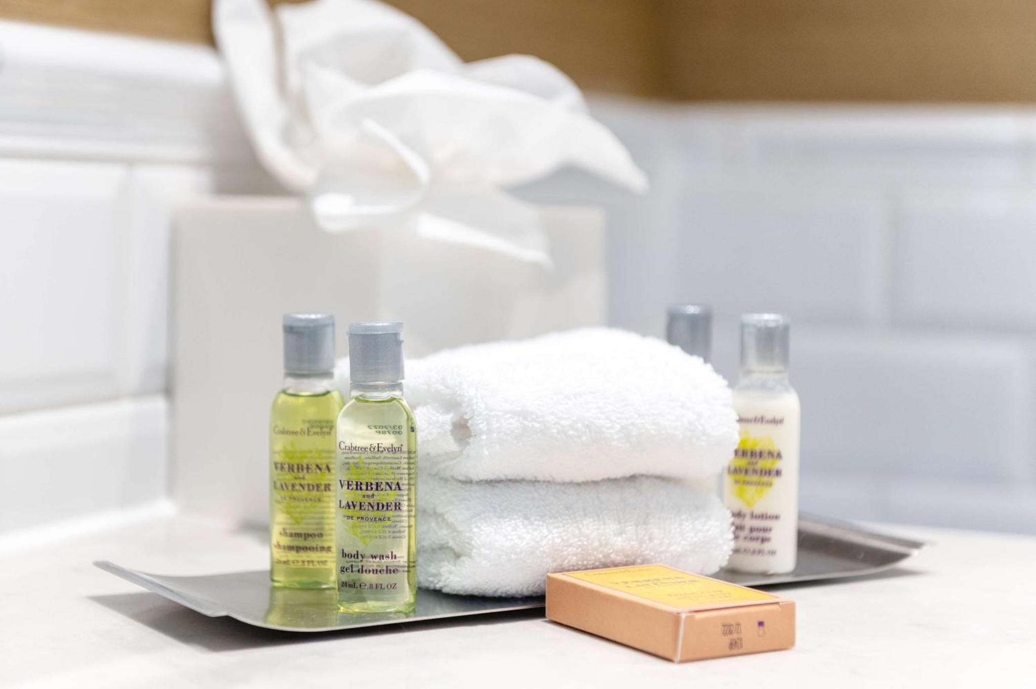 a pile of towels on a table with two bottles of soap at Hilton London Hyde Park in London