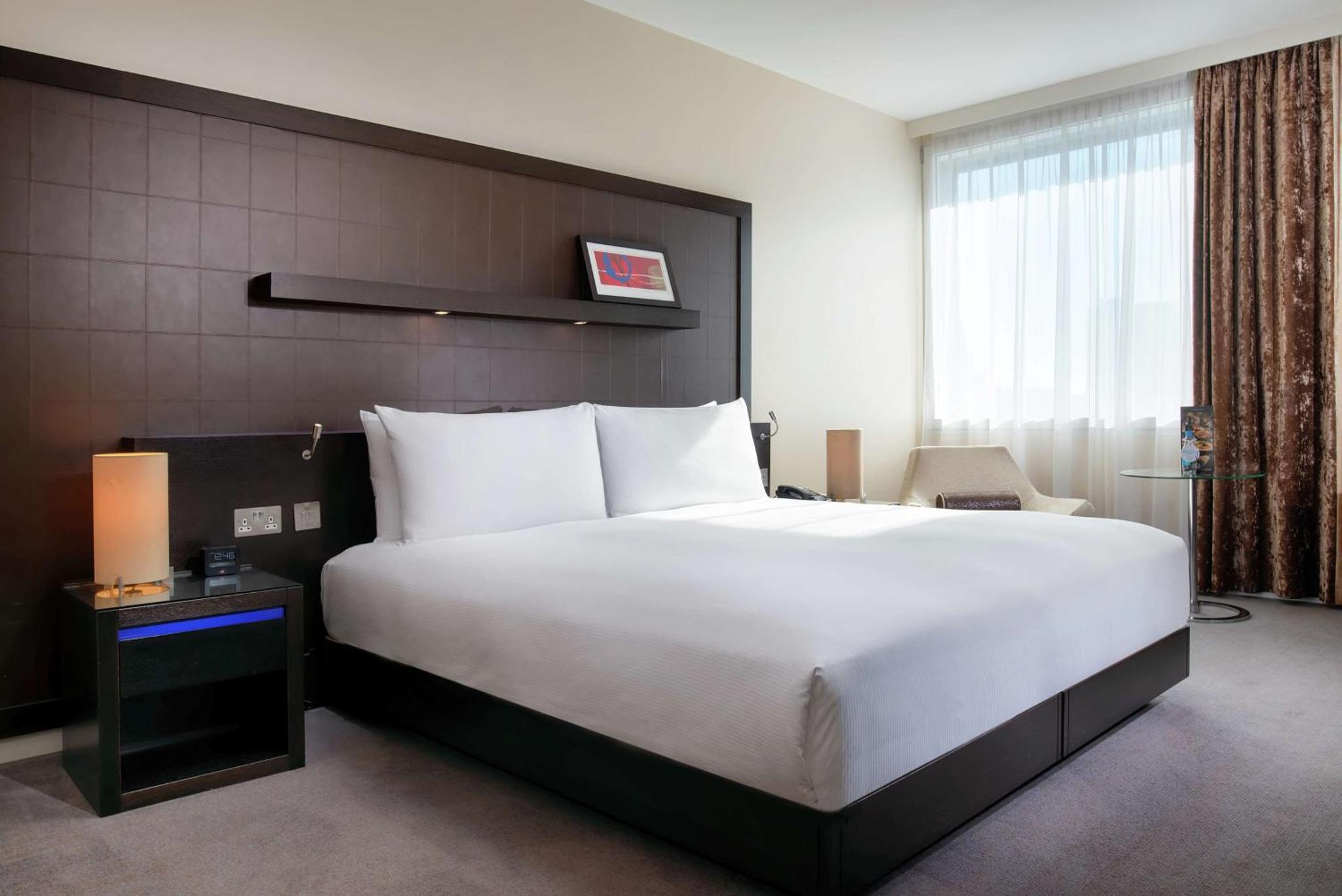 a bedroom with a large white bed and a window at Hilton London Canary Wharf in London