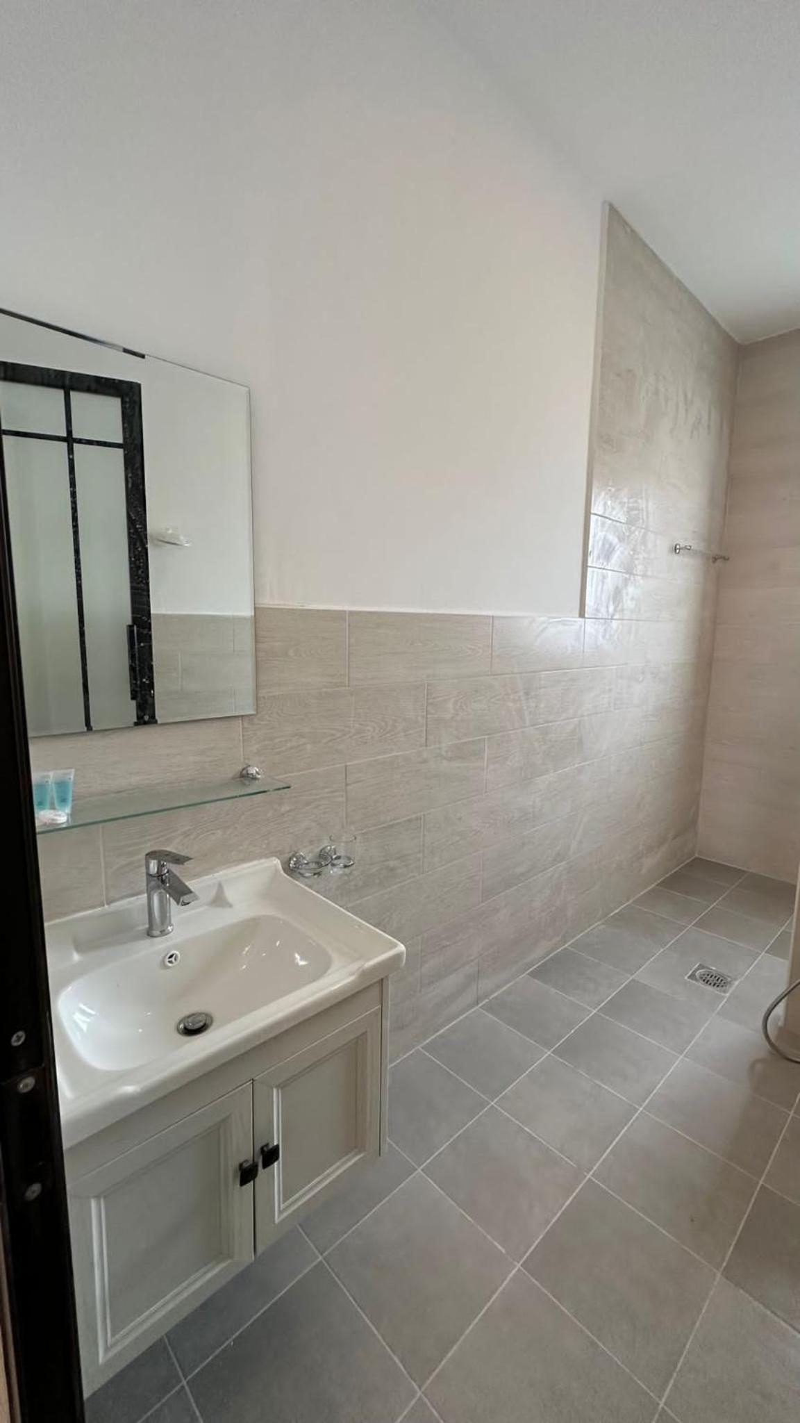 a white bathroom with a sink and a mirror at Cielo Beach Resort in Al Qaryah
