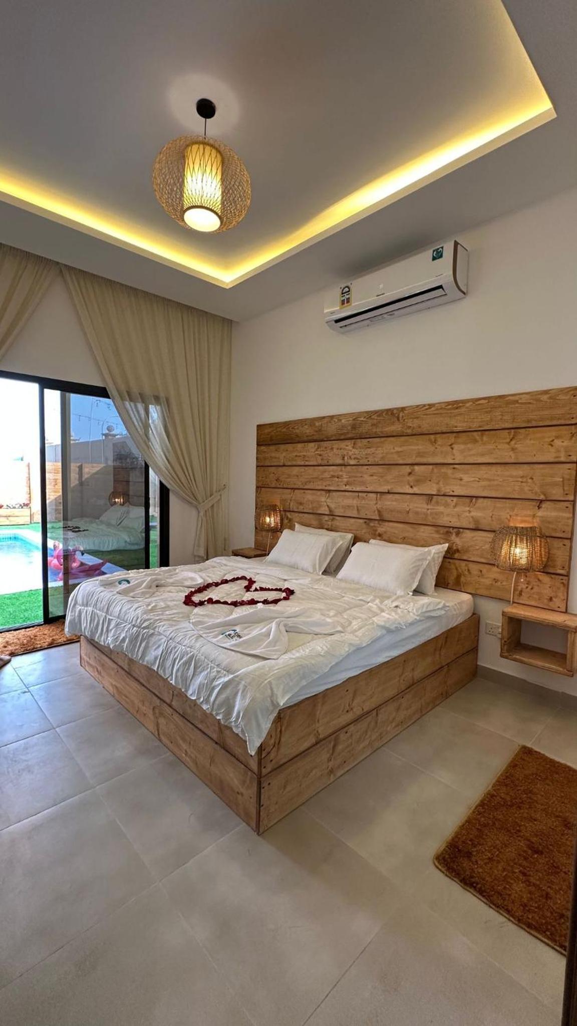 a bedroom with a large bed with a wooden headboard at Cielo Beach Resort in Al Qaryah