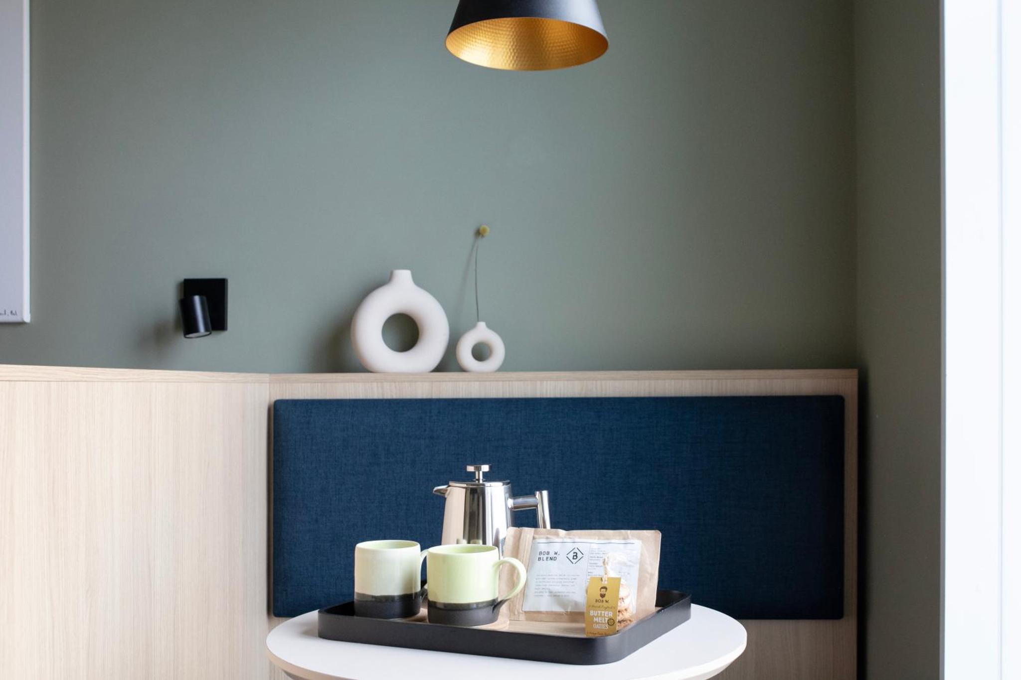 a table with cups on it with a blue wall at Bob W London Tower Hill - Studios in London