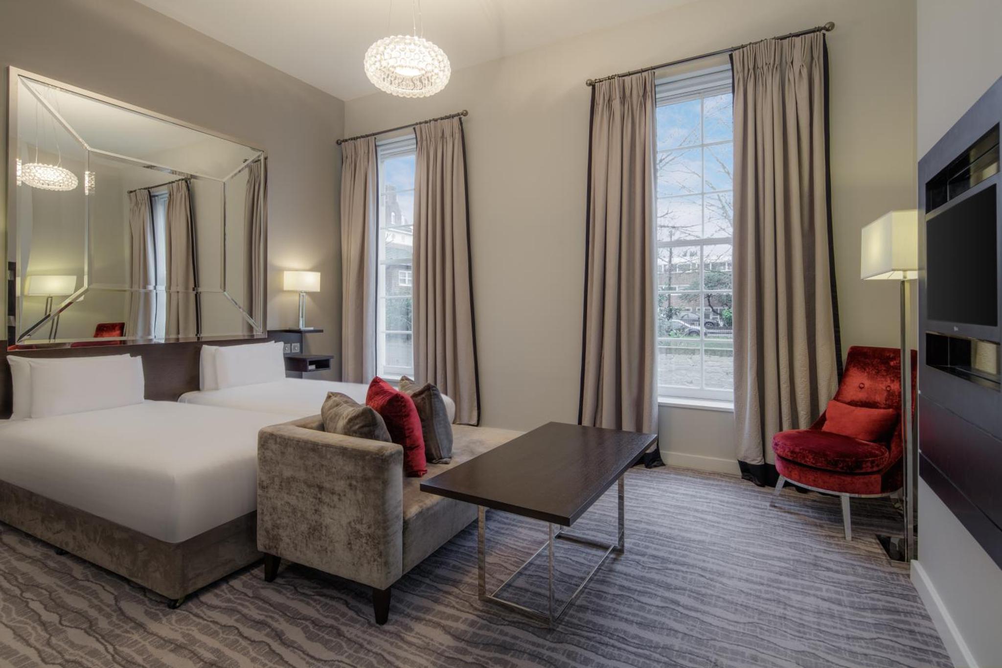 a hotel room with a bed and a couch and a table at Doubletree By Hilton London - Greenwich in London