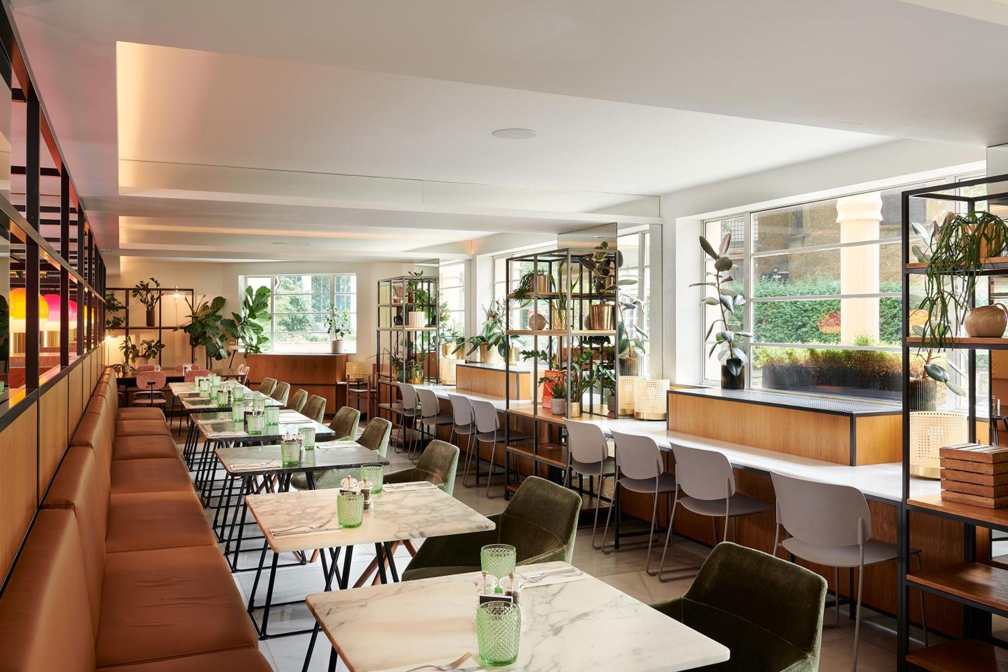 a restaurant with tables and chairs and windows at Melia White House Hotel in London