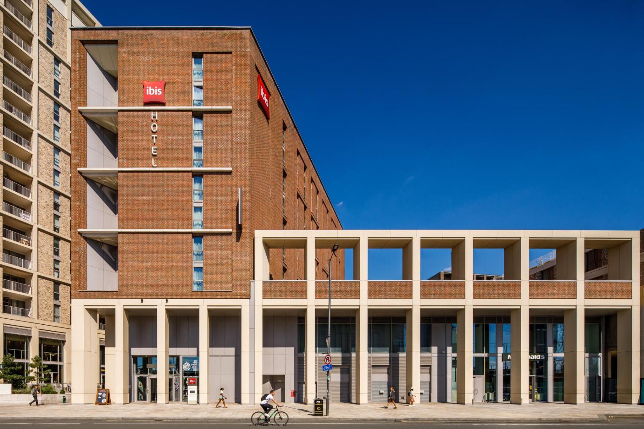 a person riding a bike in front of a building at ibis London Canning Town in London