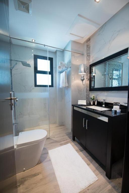 a bathroom with a toilet and a glass shower at seef manzil in Seef