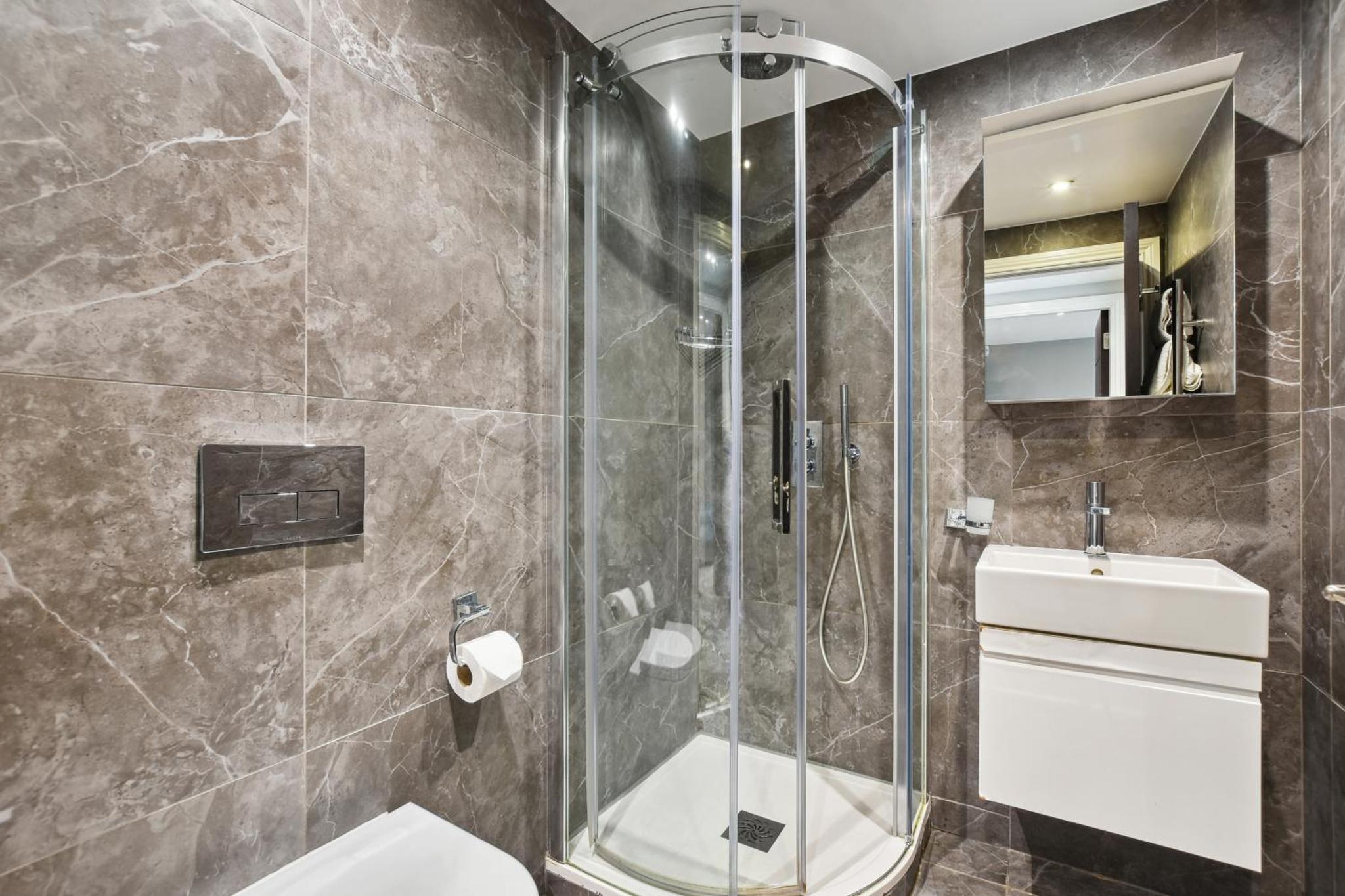a bathroom with a shower and a toilet and a sink at Buckingham Palace Residences by Aeria Apartments in London