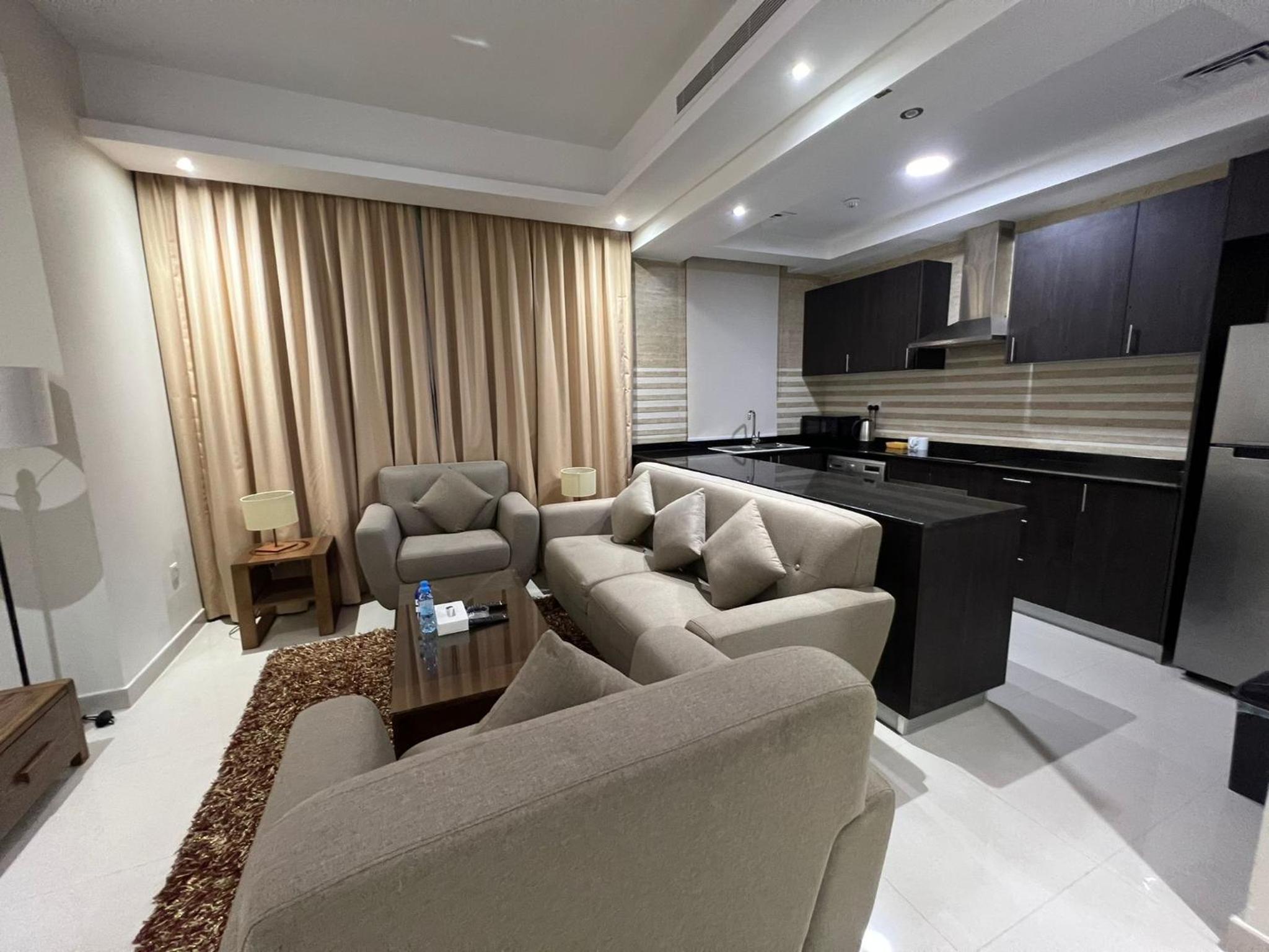 a living room with couches and chairs and a kitchen at SIRIUS TOWER in Juffair