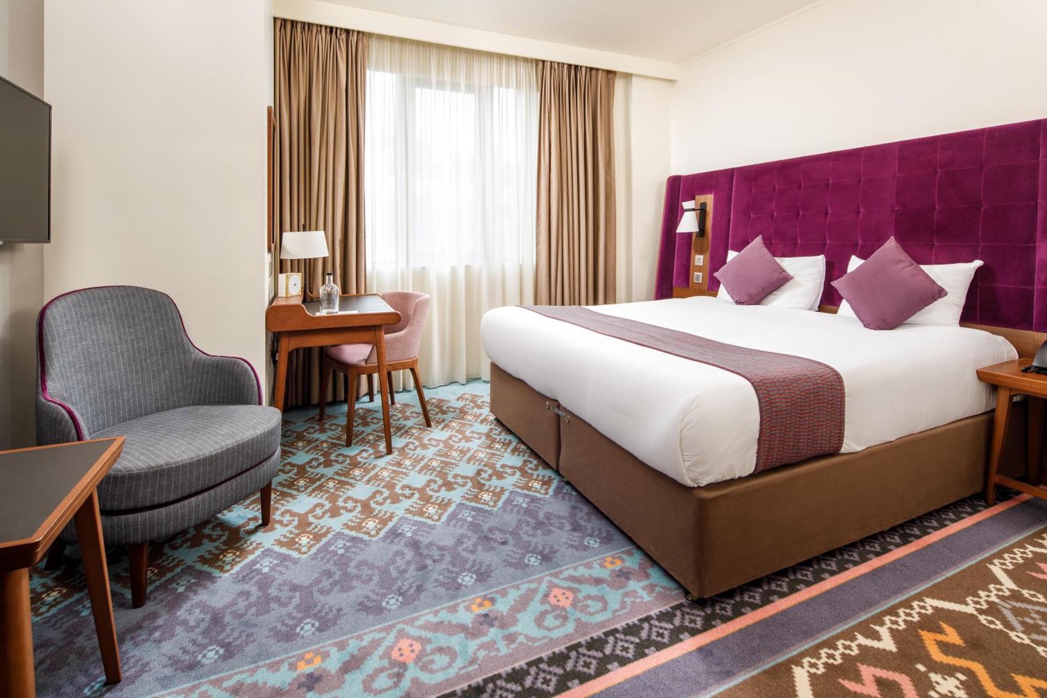 a hotel room with a large bed and a chair at Mercure London Bankside in London