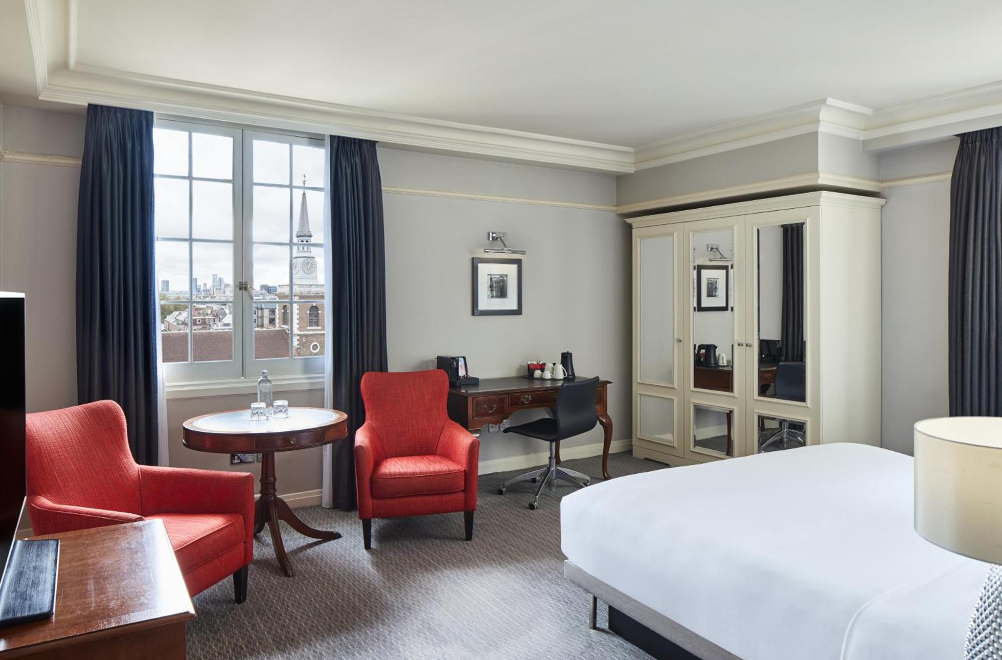 a hotel room with a bed and a desk and chairs at The Dilly in London