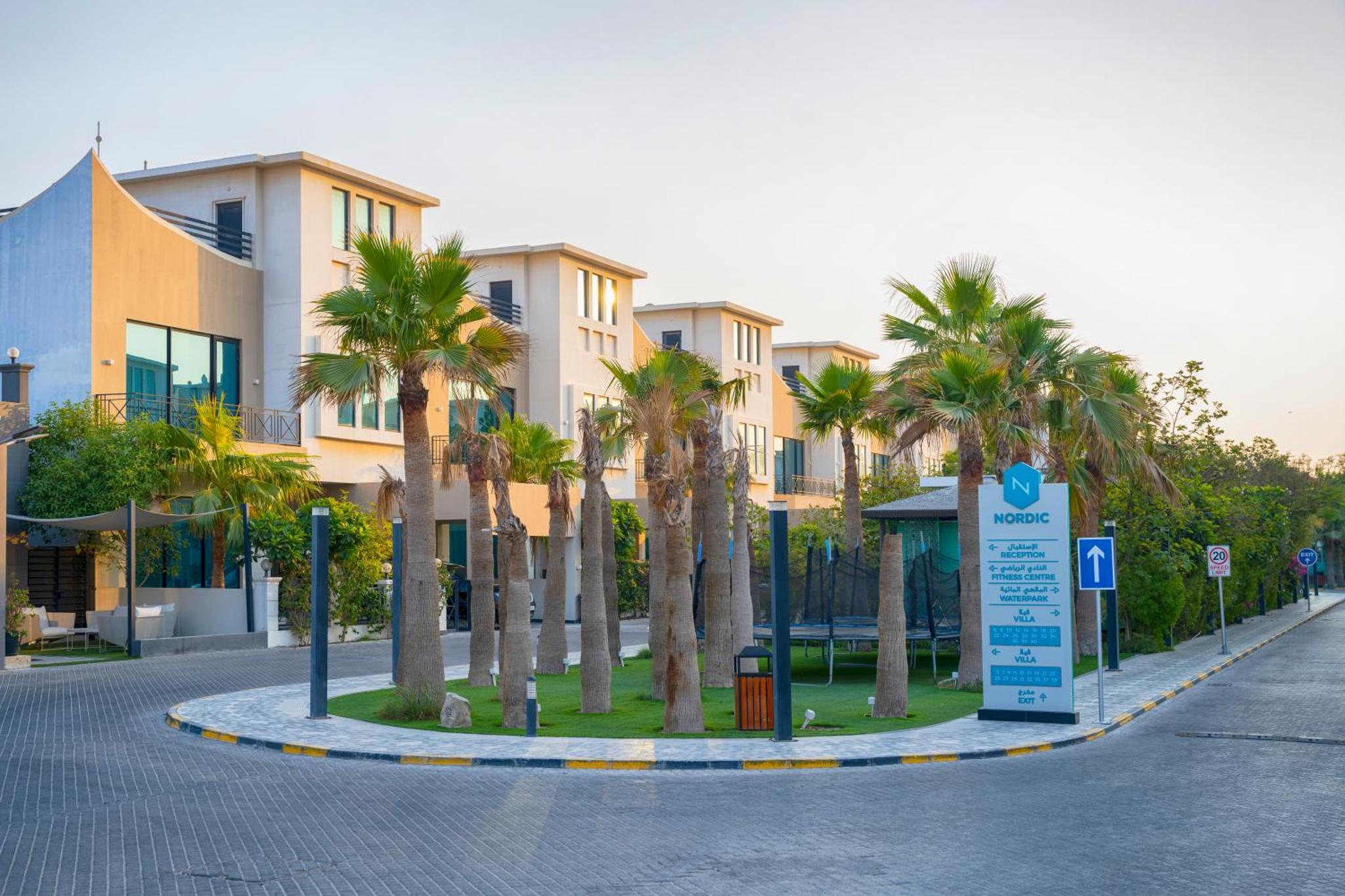 a roundabout with palm trees in front of a building at Nordic Resort in Manama